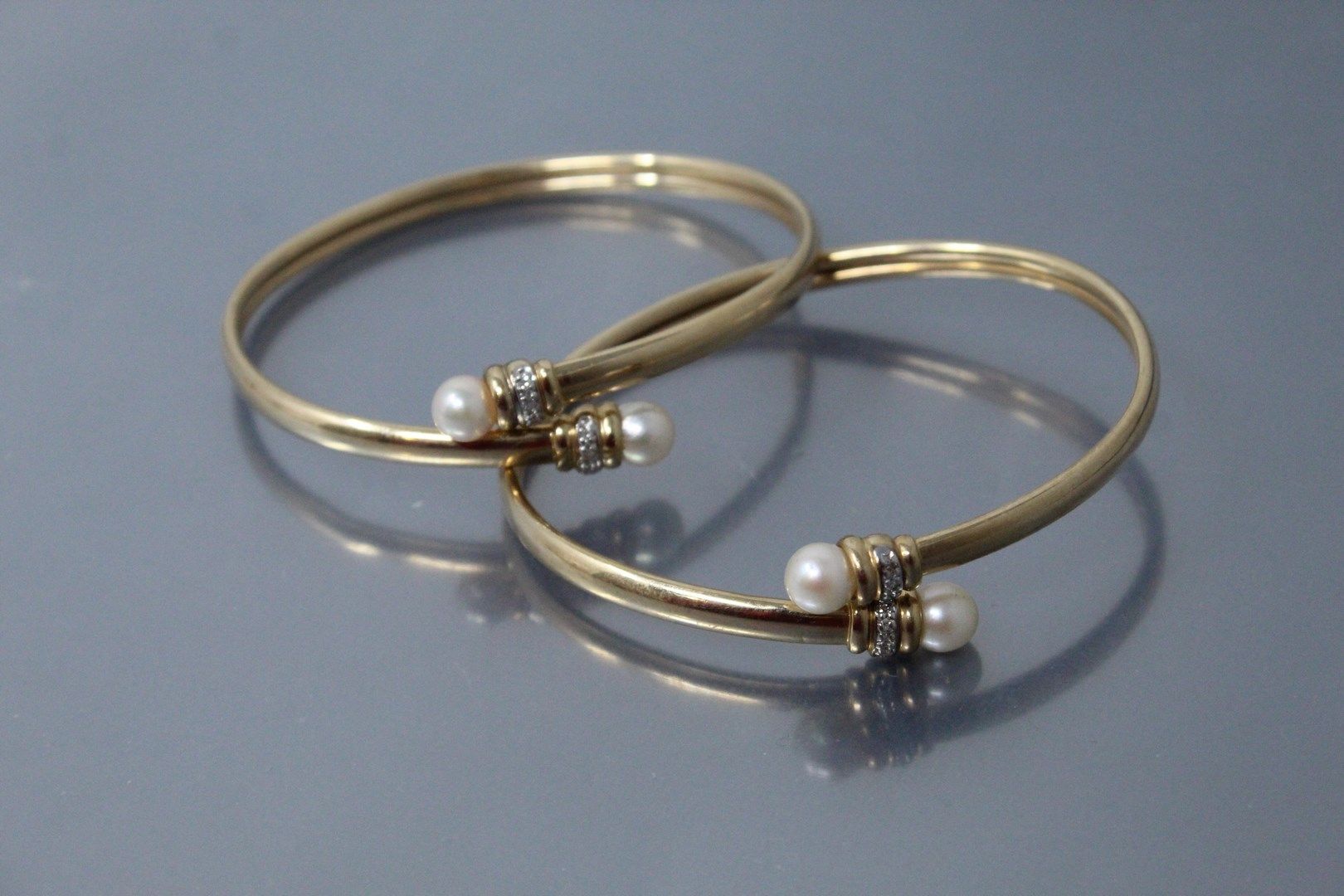 Null 一套两个14K（585）黄金手镯，每个手镯都有两颗养殖珍珠和白色石头。

毛重：11.65克。