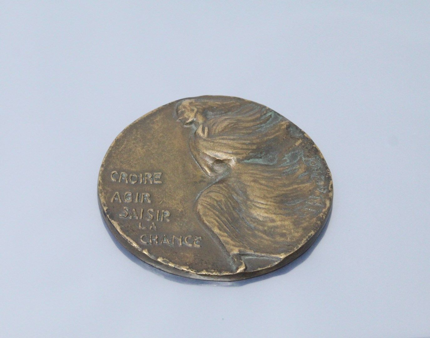 Null 单面铜牌，描绘了一个行走的女人，她的左边是 "相信/行动/抓住/机会"，出自简-布朗肖之手。边缘光滑。

直径：9厘米 - 装在箱子里。