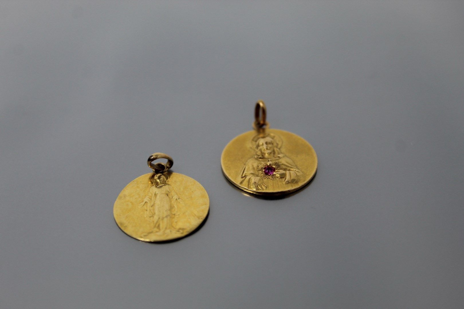 Null 一套两枚18K（750）黄金宗教奖章，一枚描绘了基督手持红宝石形成的圣心，另一枚描绘了圣母。在背面有图。

冲击和划痕。

毛重：6.70克。