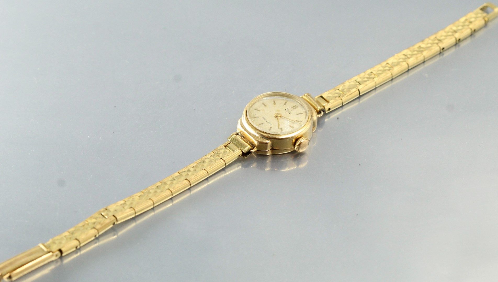 Null 女士腕表，18K（750）黄金圆形表壳，奶油色表盘和指挥棒标记。

签署VOG/Distr.的科迪

镀金金属手镯，带棘轮扣

毛重：23.38克。
&hellip;