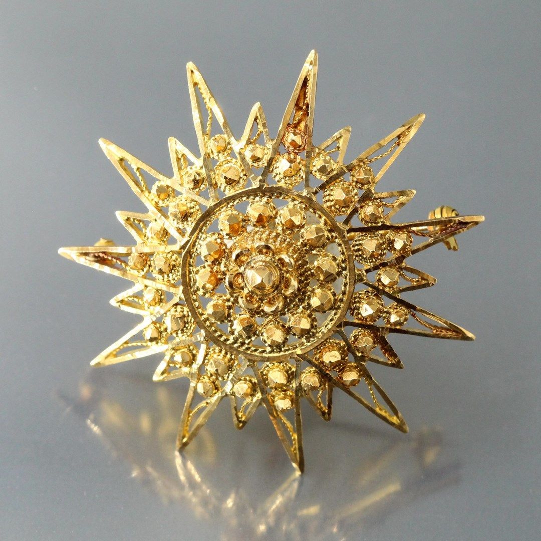 Null Broche en or jaune 18k (750) stylisant un soleil.

Poids brut : 13.59 g.