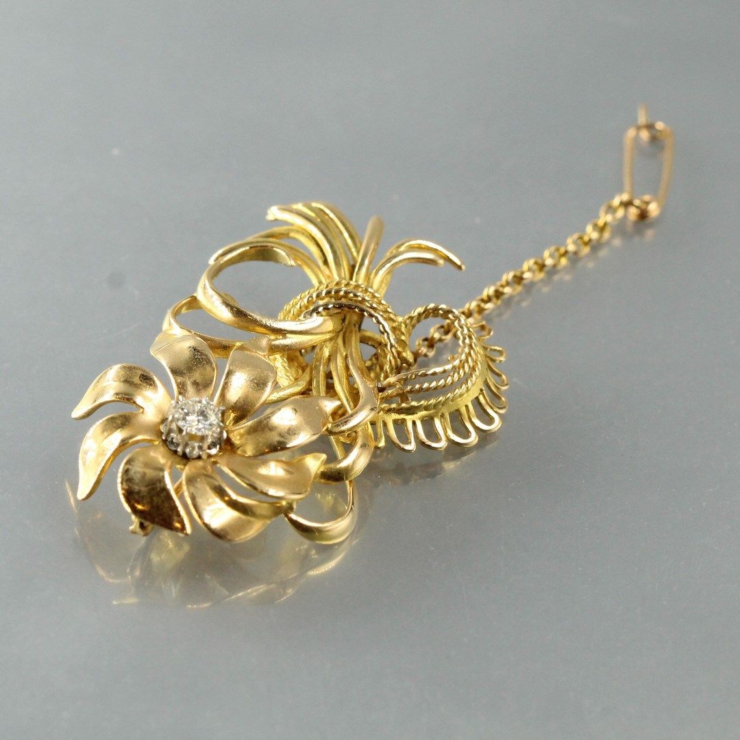 Null 18K(750)黄金胸针，造型为一朵花，花蕊上装饰着一颗圆钻。

钻石的重量：约0.15克拉。

高度：5厘米。- 毛重：15.09克。