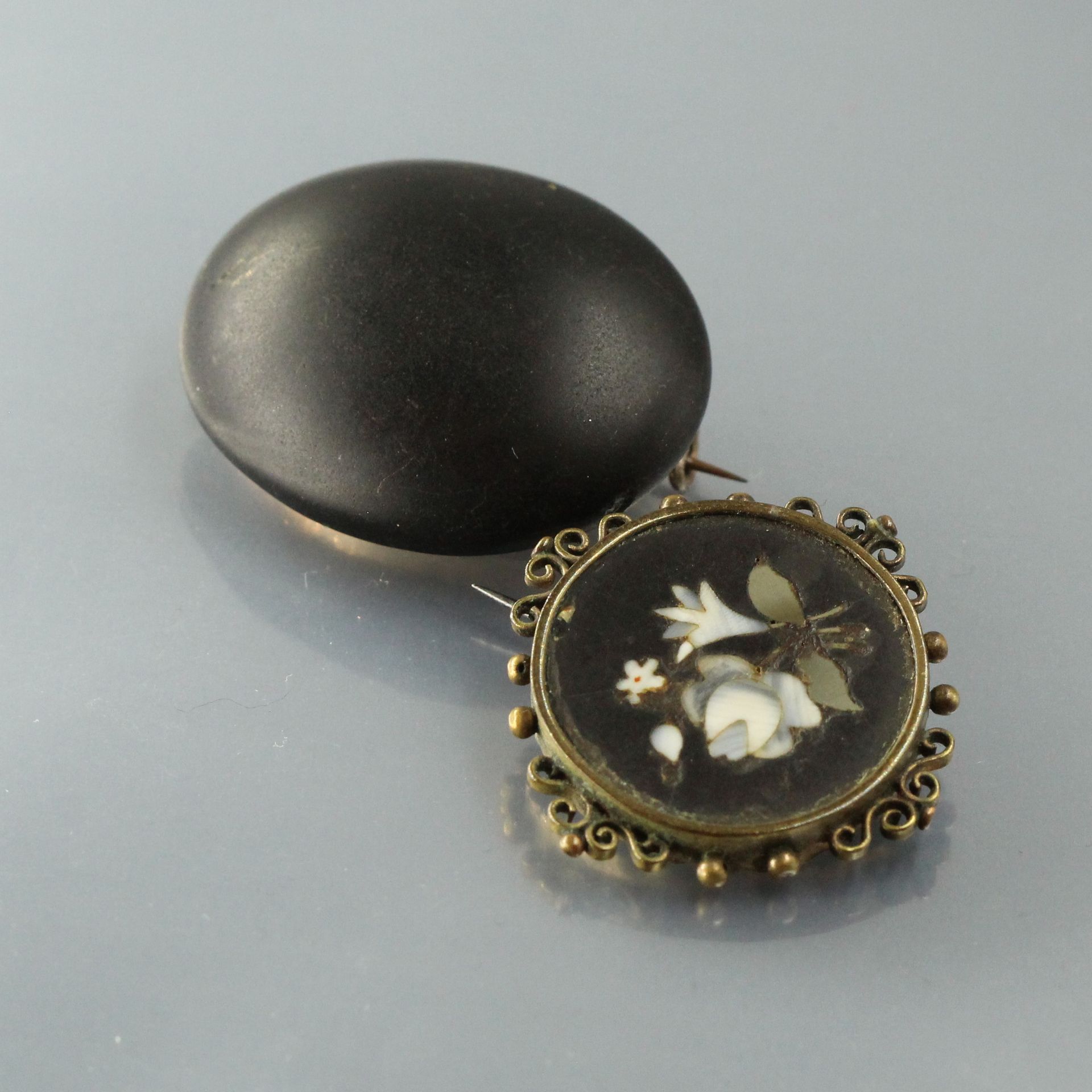 Null 镶嵌宝石的圆形胸针，带有花卉装饰，框架为镂空。19世纪的作品。

一枚椭圆形的黑色大理石哀悼胸针，银质镶嵌（野猪）。

毛重：18.50克。