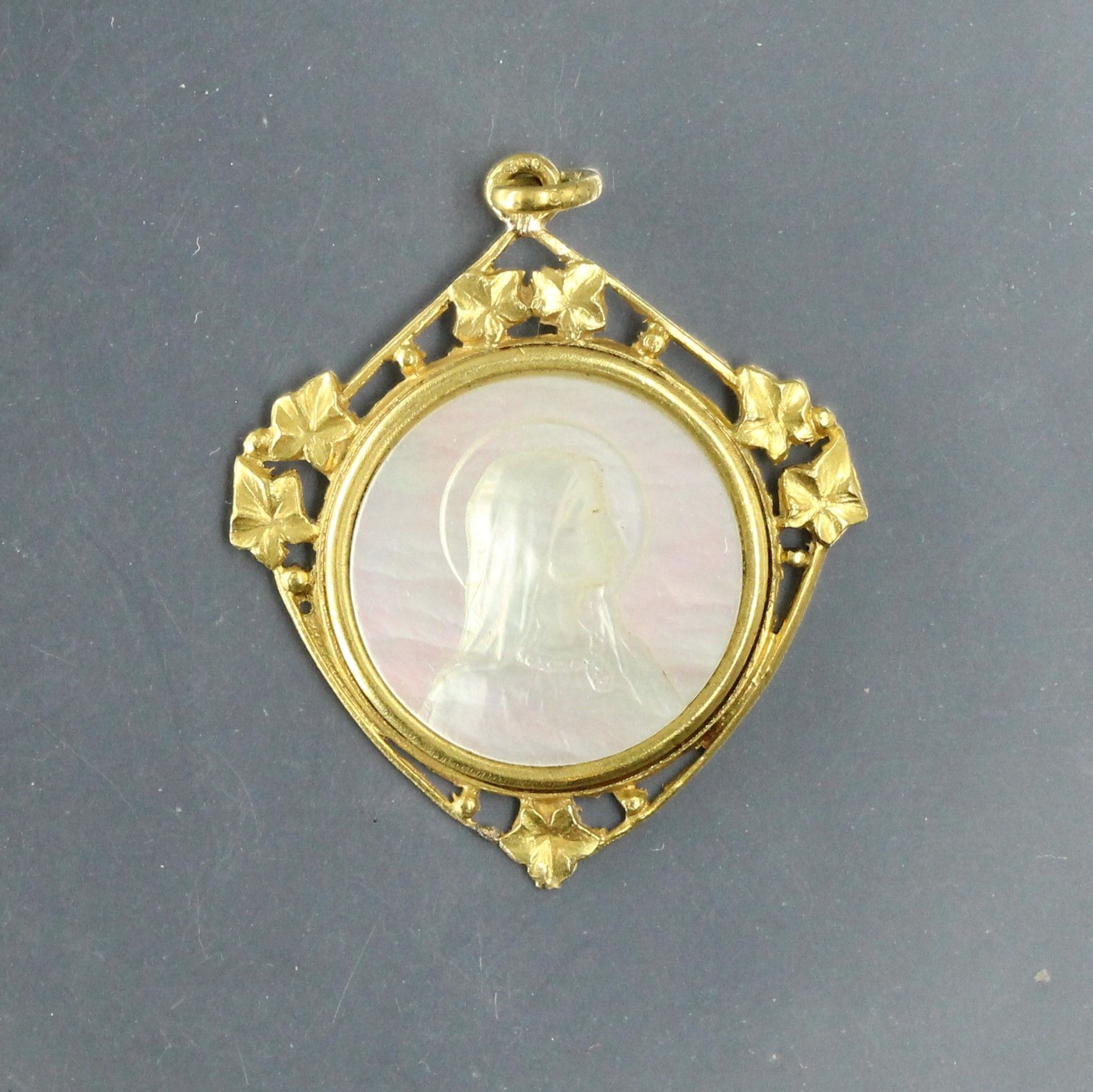 Null 一枚圆形珍珠母章，正面是圣母，背面是1922年5月18日的DM。镶嵌在18K（750）黄金上，有一个镂空的叶子设计。

有印记。

毛重：3.30克。