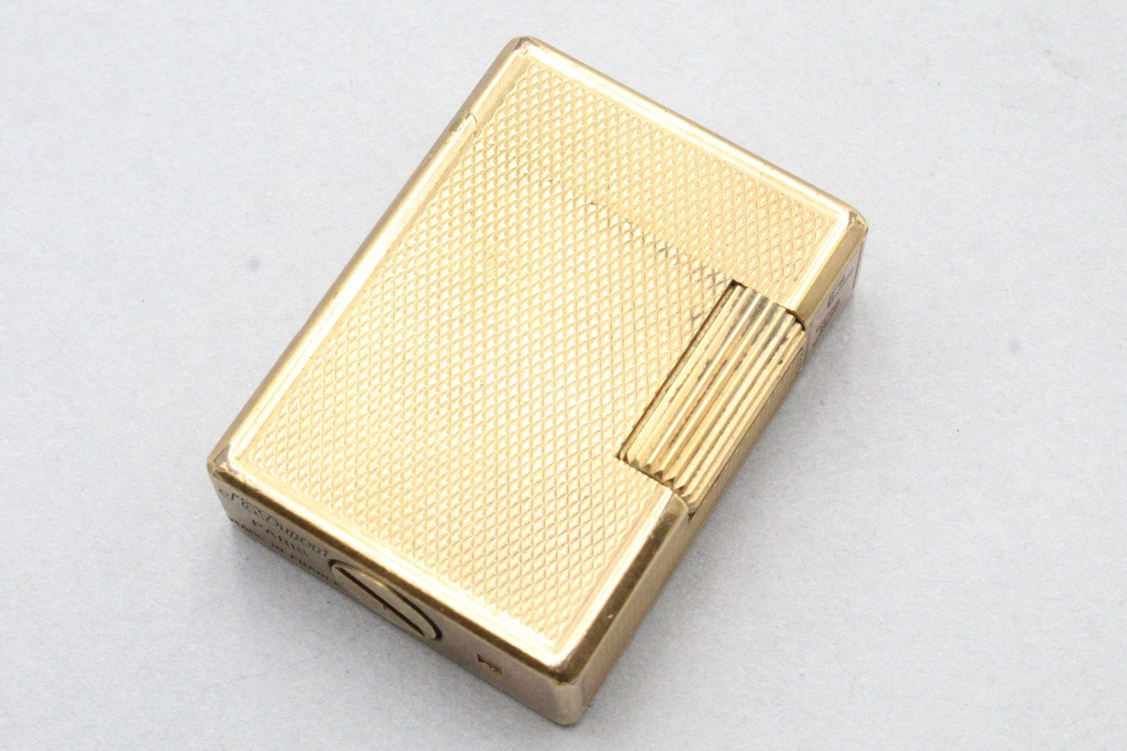 Null S.T. DUPONT 

Briquet en métal doré guilloché. 

Signé S.T. Dupont et numér&hellip;