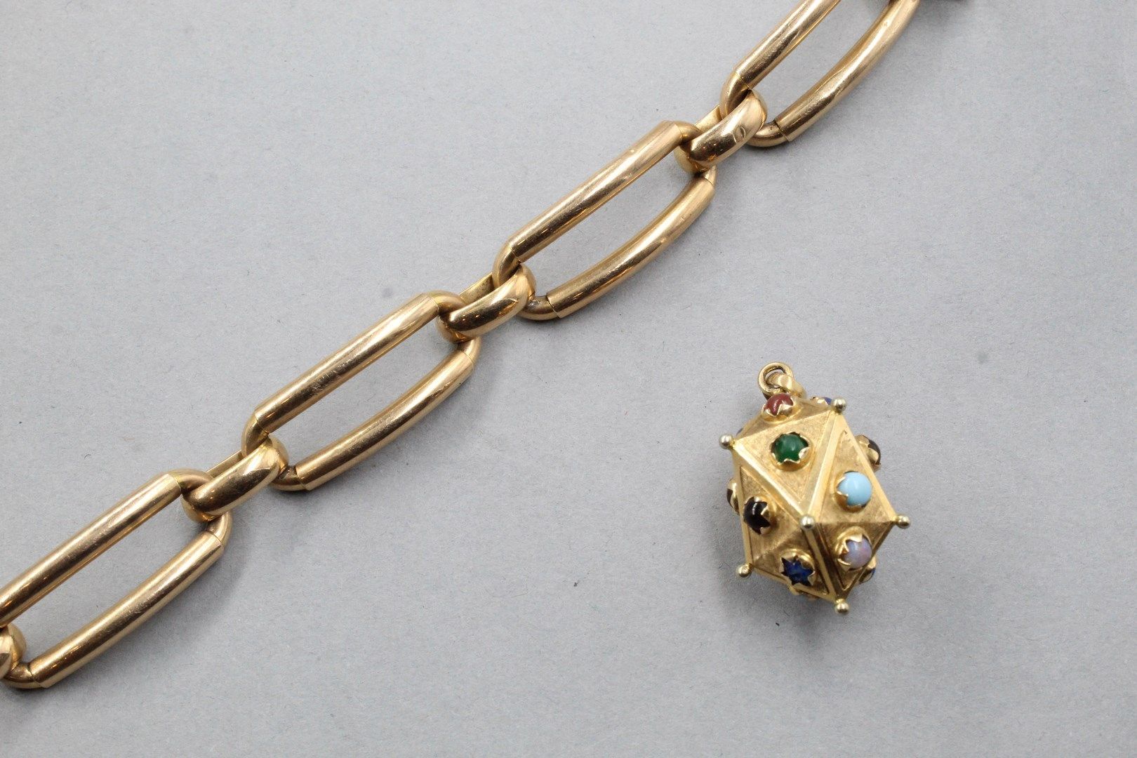 Null 18K（750）玫瑰金手镯。

手腕尺寸：约20.5厘米

附有一个18K黄金吊坠，上面有装饰性的凸圆形宝石。

毛重：24.40克。