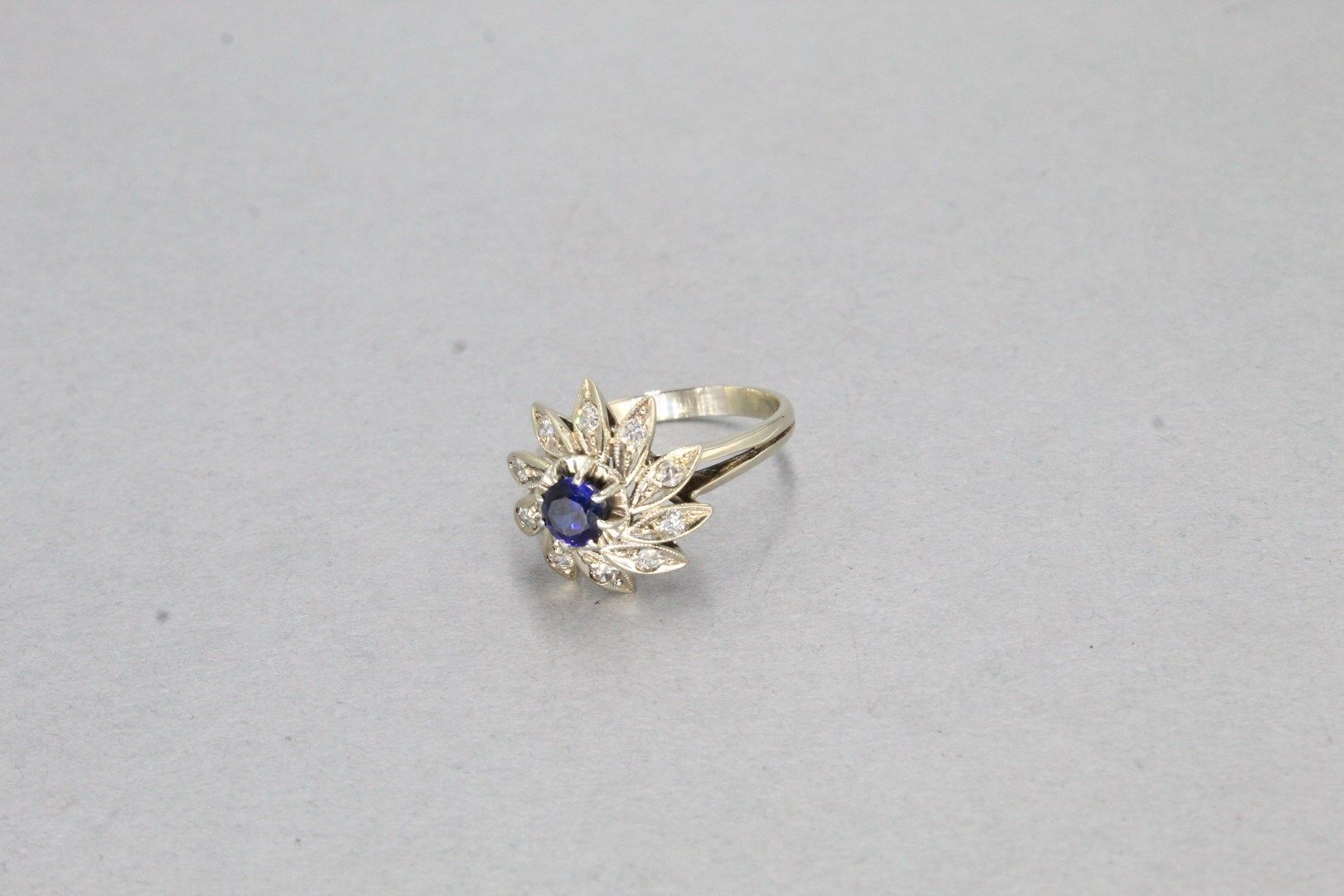 Null 18K(750)白金花戒，镶有蓝色仿石，花瓣上镶有老式切割钻石。

标有一个鹰头。

手指大小：53 - 毛重：5.04g。