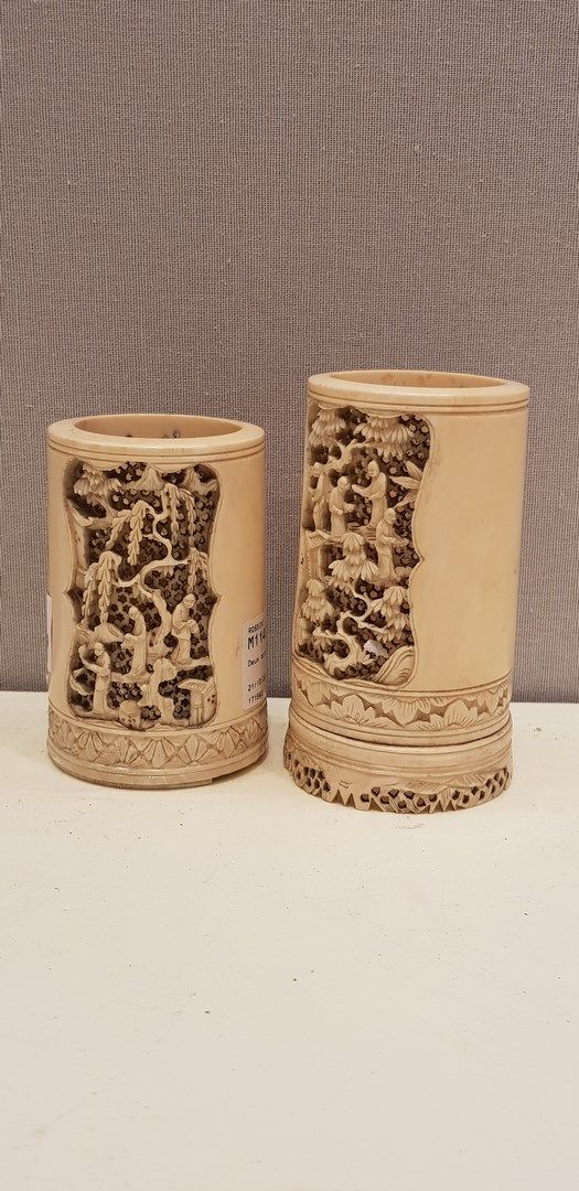 Null 
中国 - 20世纪初

两只由一段象牙雕刻而成的圆柱形壶，放置在一个底座上。竹林七贤的镂空装饰。

高：11厘米

事故