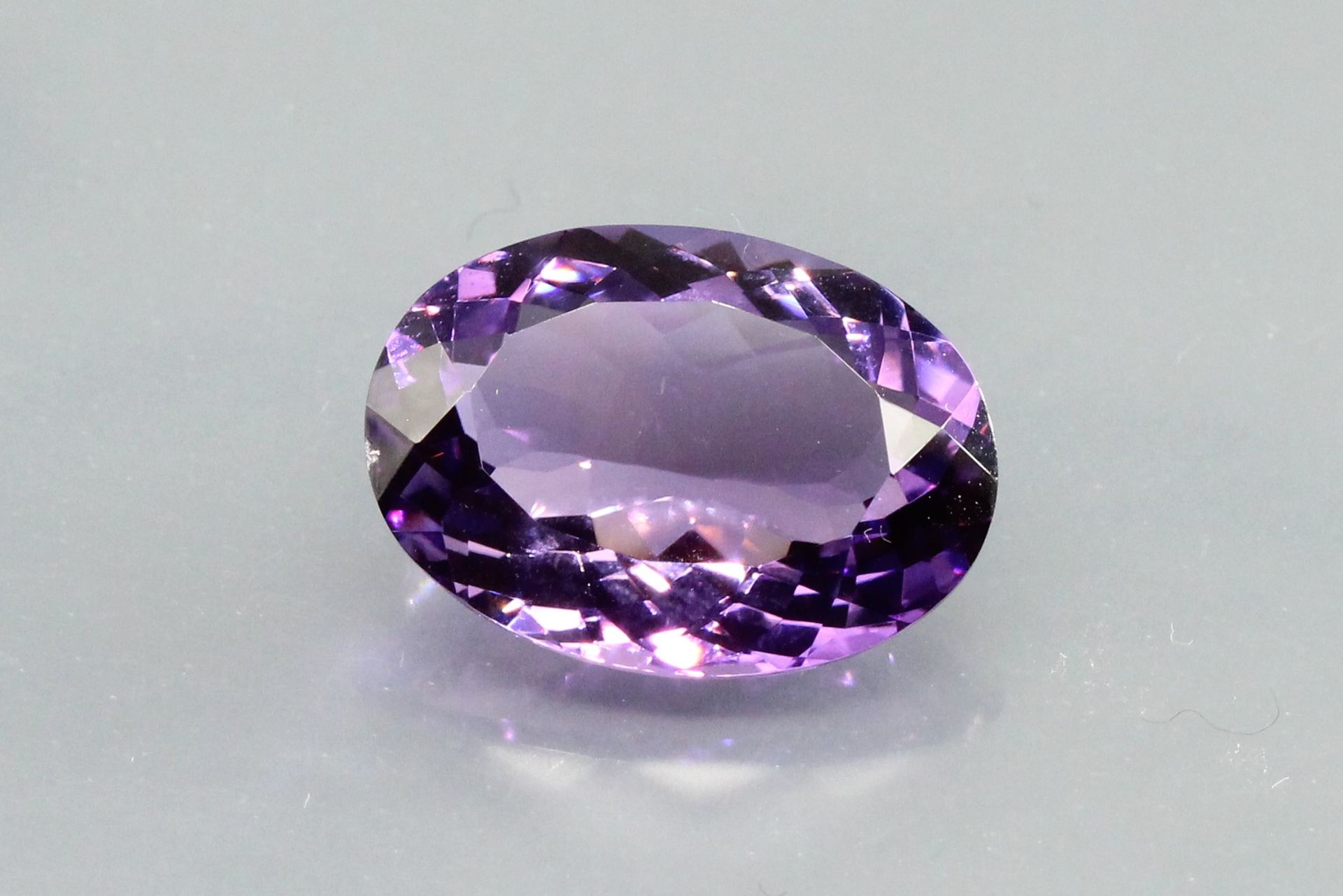 Null 椭圆形紫水晶在纸上。

重量：11,46克拉。