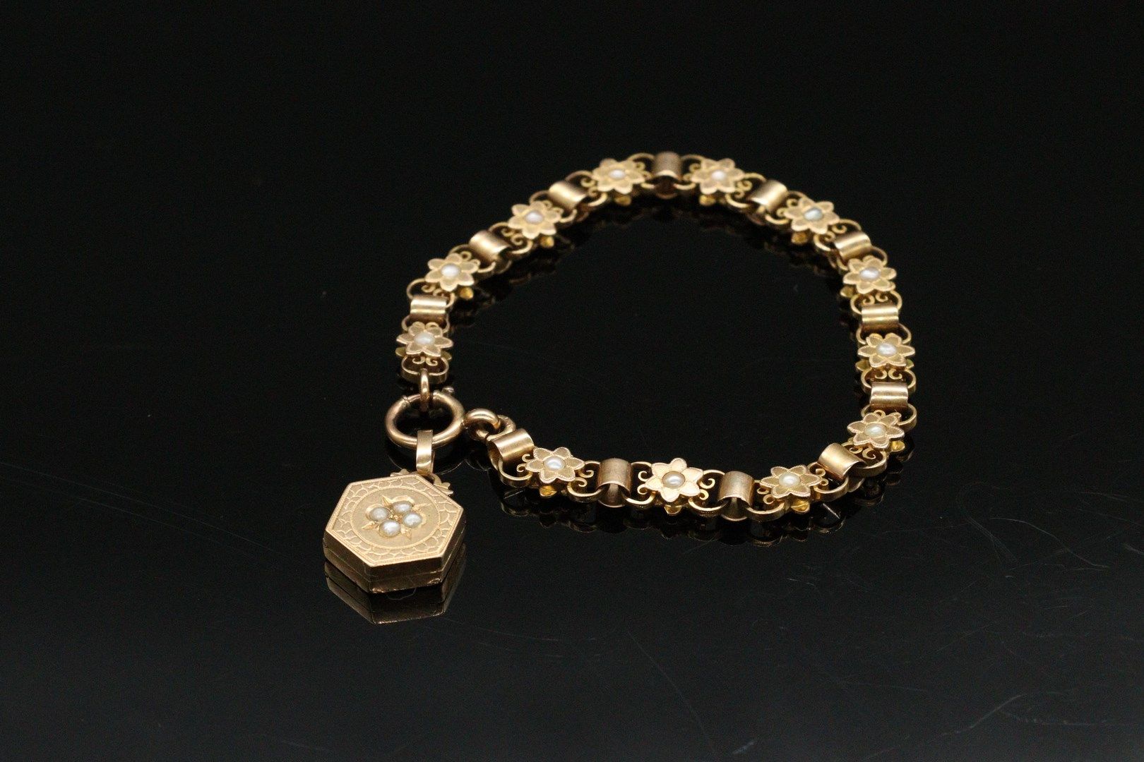 Null 一条18K(750)黄金手链，其扣子上有一个图片奖章。链节由饰有珍珠的玫瑰花组成。 

毛重：17.36克。