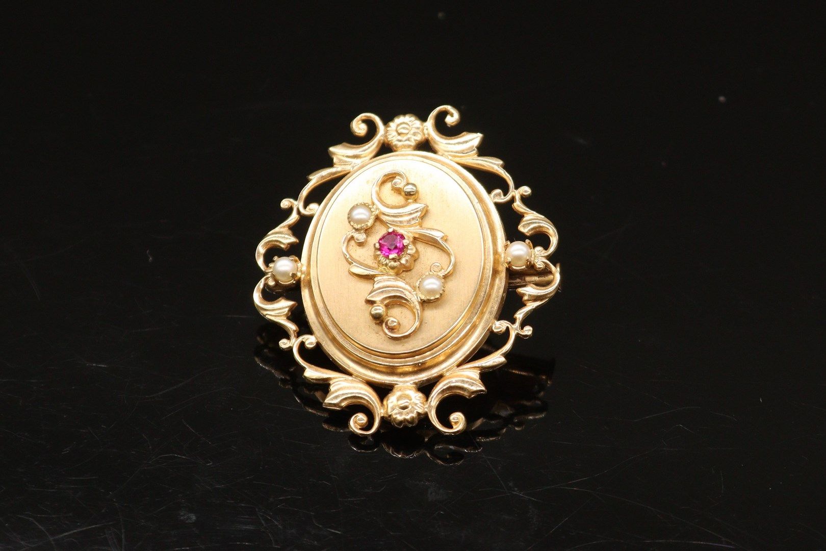 Null 一枚18K(750)黄金椭圆吊坠胸针，上面有卷轴和小珍珠，中间有一颗小红宝石。

毛重：6.7克。