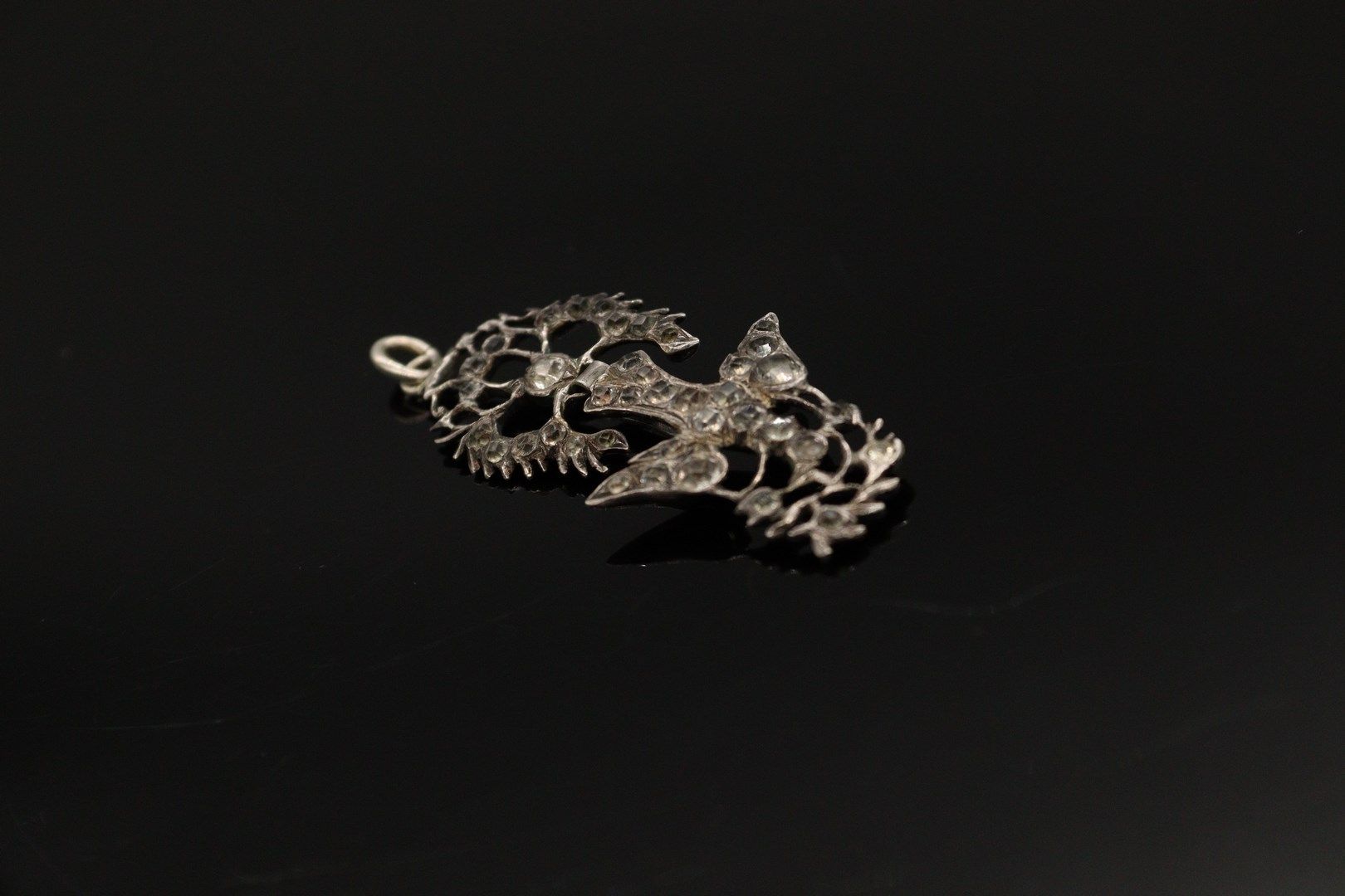 Null 银质（800）"诺曼底的圣灵 "胸针-吊坠，装饰有白色水钻，由一只被打结的丝带牵着的鸽子组成，嘴里叼着一根树枝。

以野猪为标记。

长度：7厘米。
&hellip;
