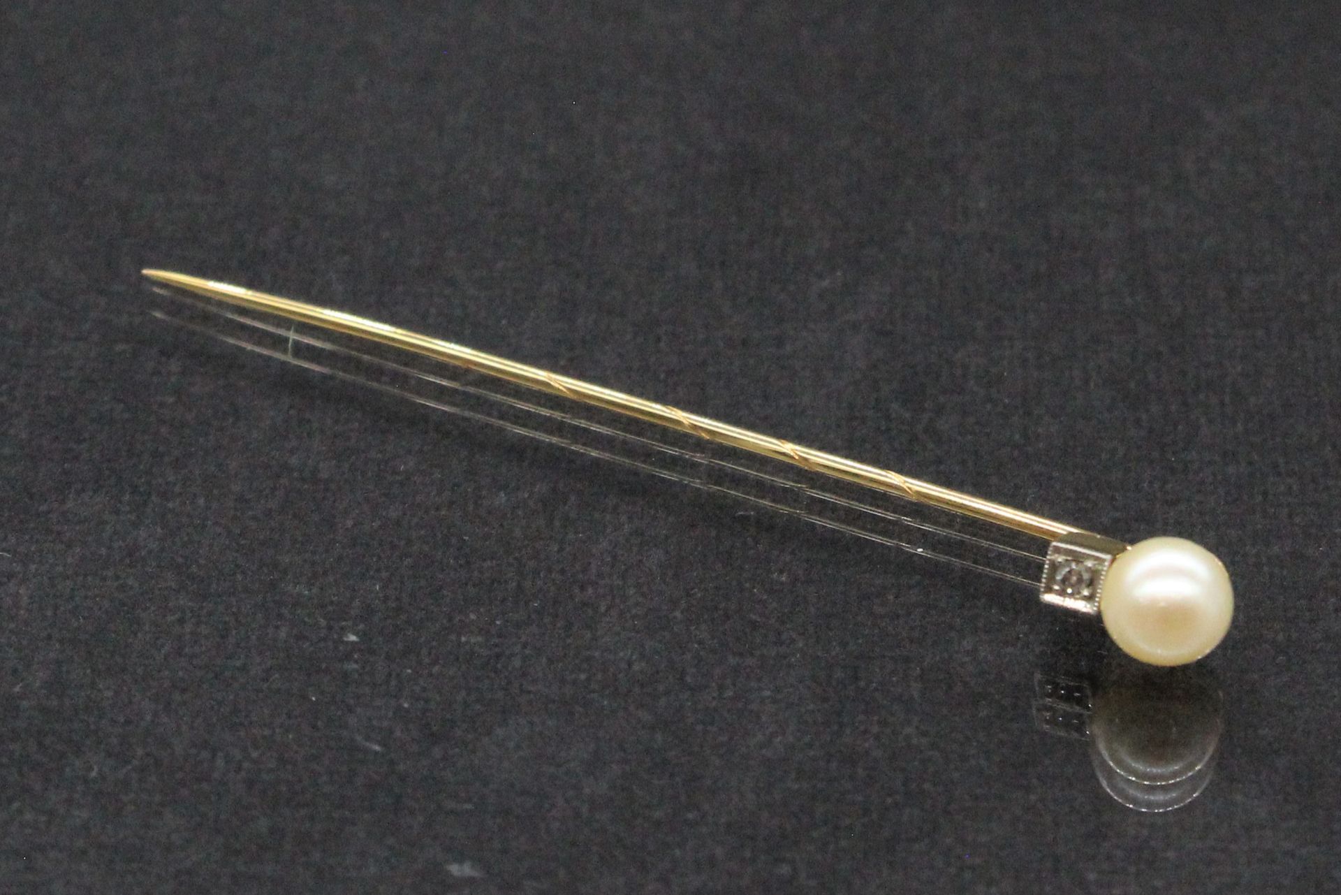 Null 18K(750)黄金针，末端有一颗小钻石和一颗养殖珍珠。

毛重：1.82克。在一个案例中。