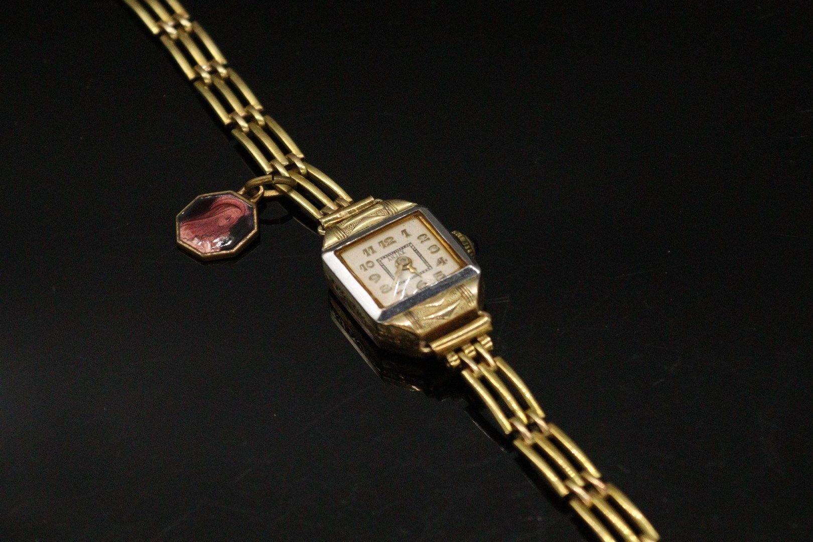Null 镀金和镀银金属女式腕表，方形表壳，白色表盘，阿拉伯数字，金属表带上有一个显示圣母的小吊坠。

直径：15毫米