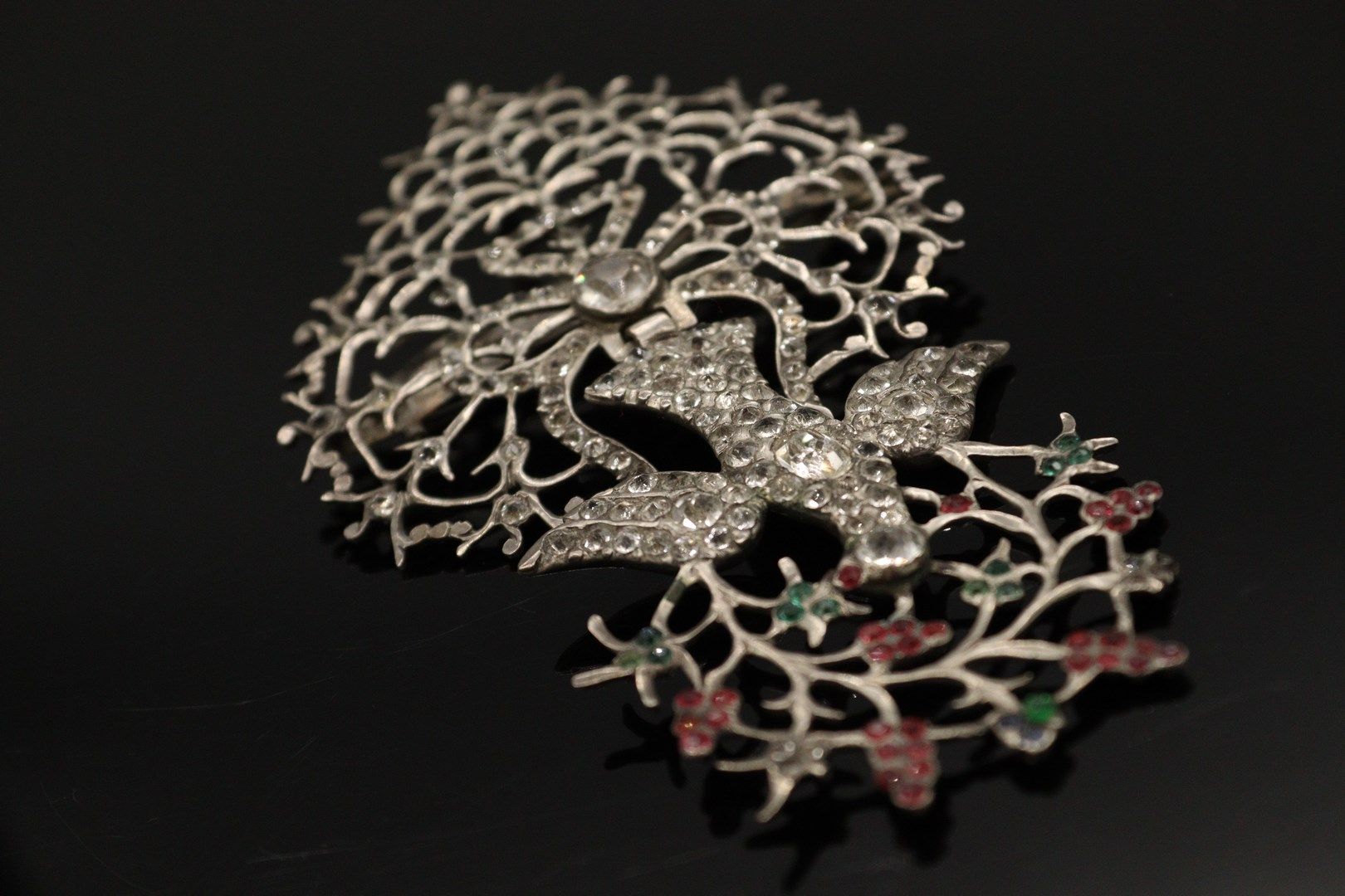 Null 银质（800）"诺曼圣灵 "胸针-吊坠，装饰有白色和彩色水钻。 它由一只鸽子组成，用打结的丝带固定，嘴里叼着藤蔓枝条。

标记：缺席。

长度：10厘&hellip;