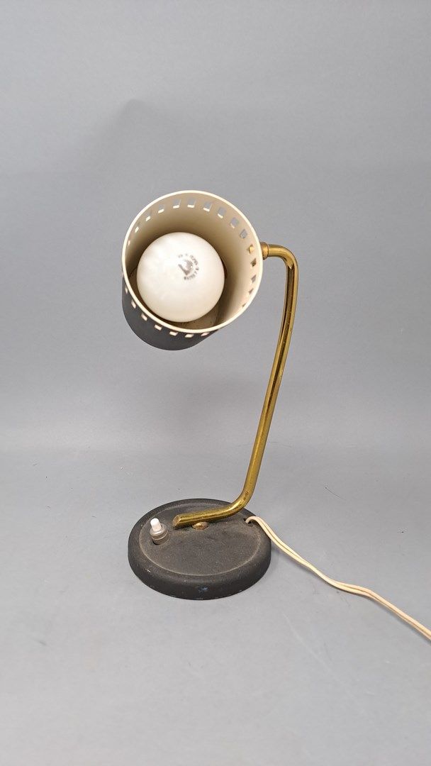 Null 哑光黑漆金属板的小台灯，镂空的灯泡盖可以通过一个球形接头调节，通过一个镀金的金属杆连接到圆形底座上。约1960年。

高度：22厘米。