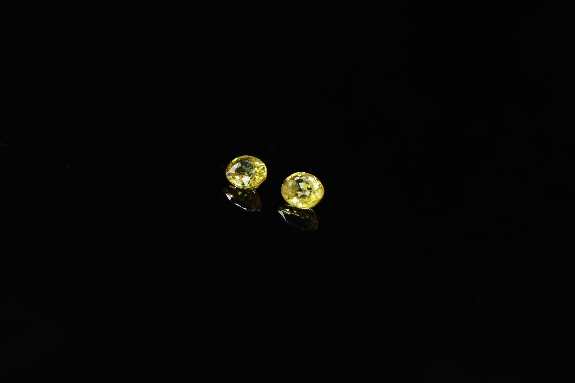 Null 一对椭圆形鲜艳的黄色蓝宝石在纸上。

总重量：0.73克拉。



平均尺寸：4.5 mm x 4 mm