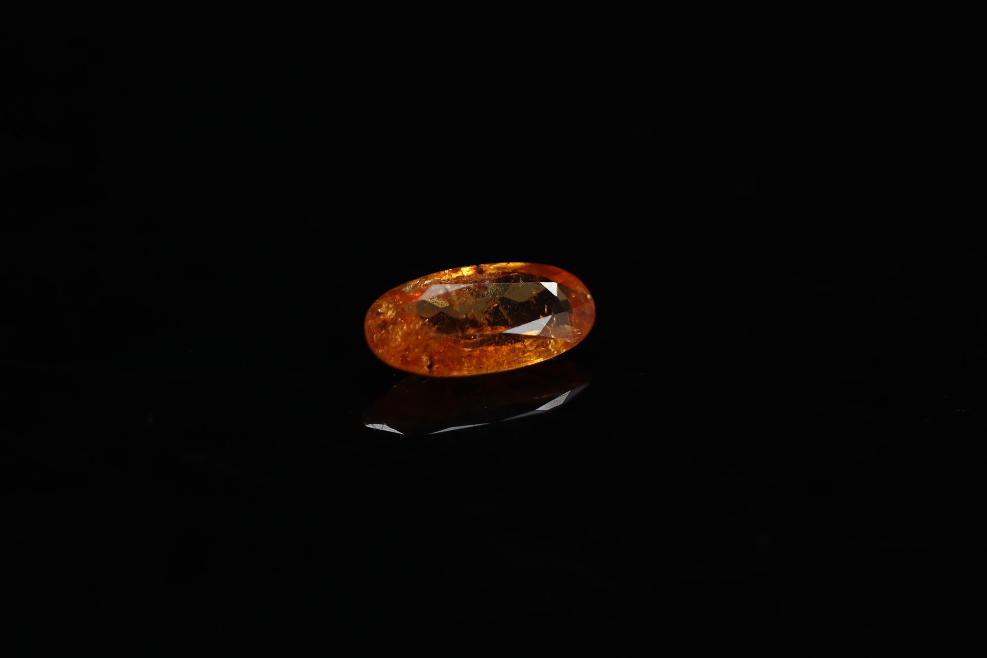 Null 椭圆形的橙色石榴石在纸上。

内含物。

重量：2.07克拉。



尺寸：11.3 mm x 5.6 mm