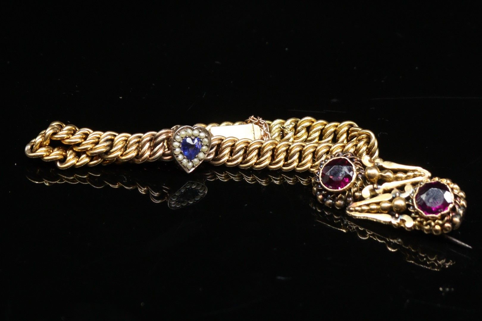 Null 镀金手镯（铰链式），一颗心镶嵌着蓝色合成宝石，中间有小珍珠装饰，安全链。

毛重：8.70克。

附有一个镶有两颗紫罗兰宝石的小型镀金胸针。