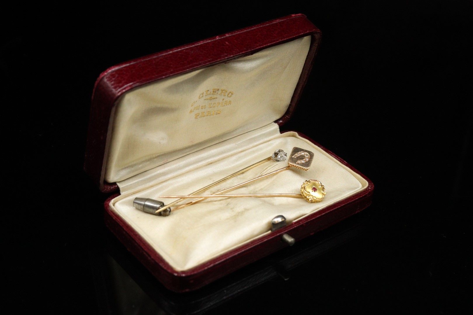 Null 一套三个18K(750)黄金领带夹，一个有切面的白色石头，一个有小红宝石，一个有马蹄形钻石。

毛重：4.55克。
