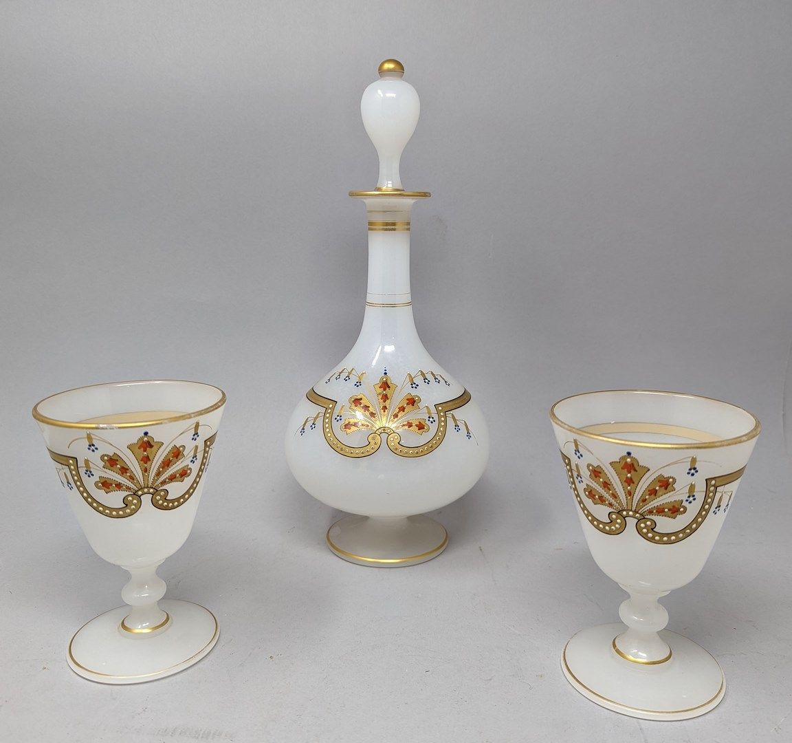 Null 一个基座上的利口酒瓶和两个乳白色玻璃的有柄酒杯，上面有镀金和部分珐琅的棕榈。19世纪晚期。

咖啡壶的高度：30厘米。