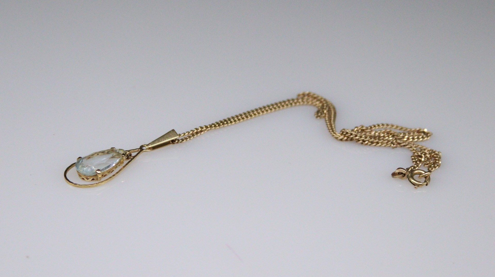 Null 18K(750)黄金吊坠，带有一颗梨形海蓝宝石。 
毛重：2.26克。 
附有一条镀金的金属链，上面有路牙链。