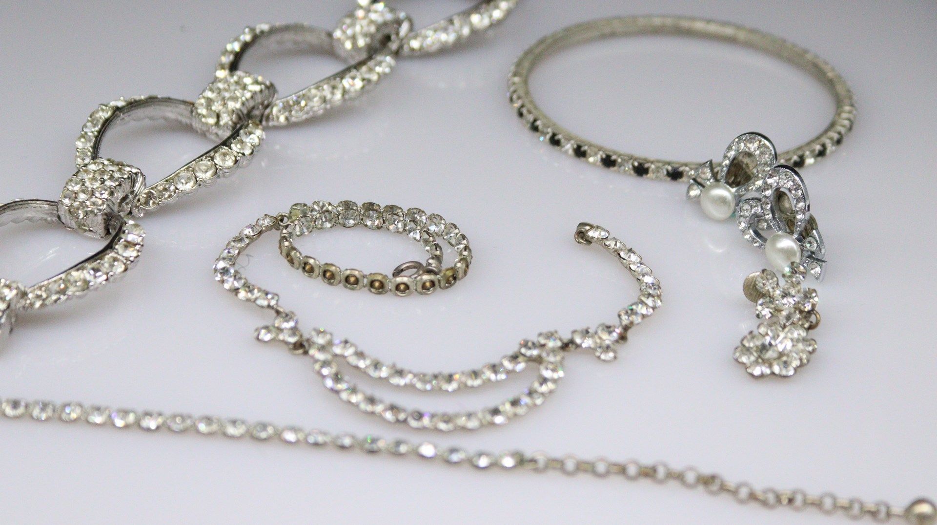 Null 一套镀银的服装首饰，包括两个手镯，一条项链，一对夹子和一个孤儿耳环，镶有白色宝石。