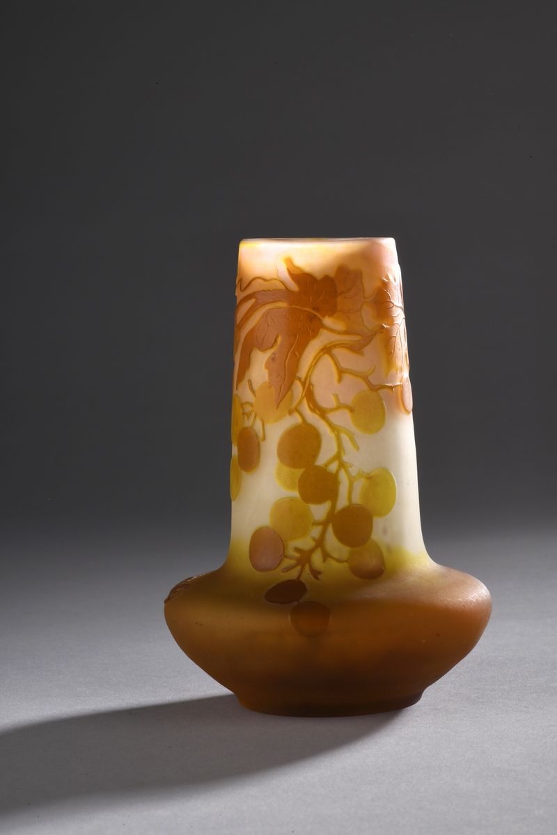 Null 加勒公司
膨胀的底座上的管状花瓶。在粉黄色的背景上用橙褐色的内衬玻璃证明。酸蚀浮雕的藤蔓和葡萄藤。 
已签名。
高度：13厘米