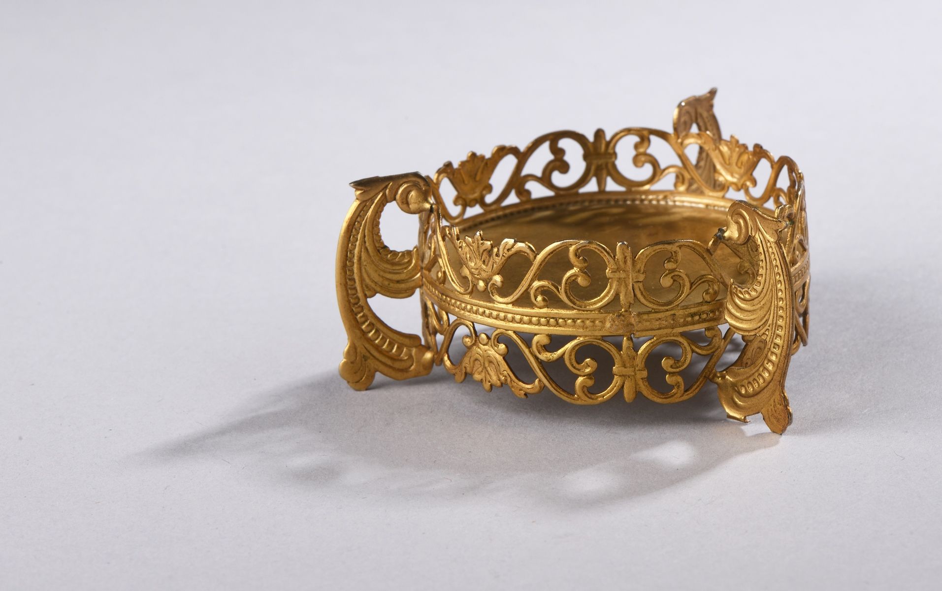 Null 一个圆形的鎏金金属糖果盒，上面有丰富的交错和珍珠楣的镂空装饰。它放置在三个滚动的脚上。
20世纪
H.3 cm - L. 6,5 cm

附上一张由雅&hellip;