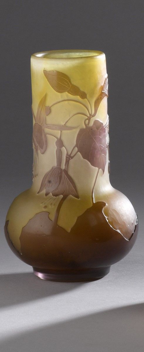 Null 加勒公司
管状花瓶，膨胀的底座上有一个环形的鞋跟。在黄橙色的背景上有紫色玻璃的证明。紫红色的装饰是用酸液浮雕的。
已签名。
高15,5厘米