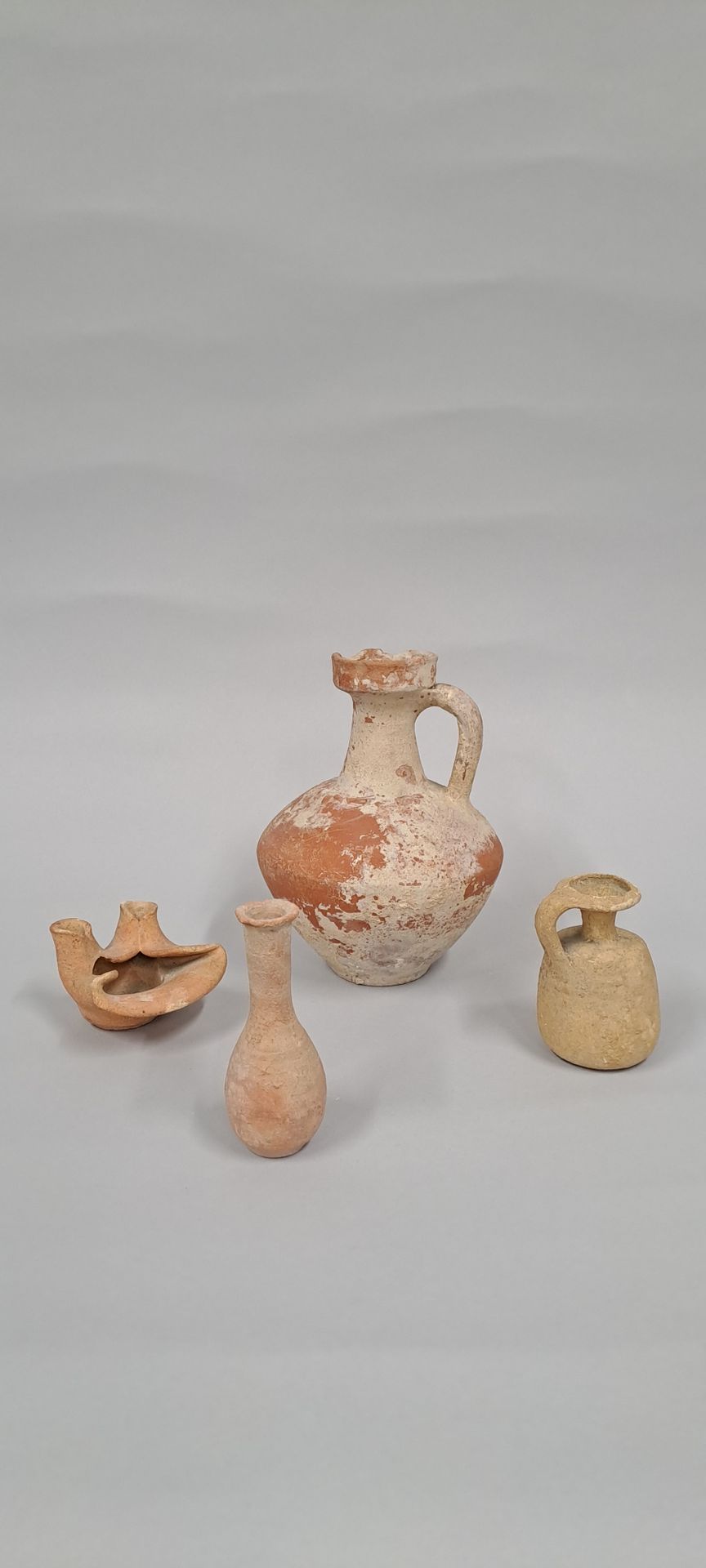 Null 拍品包括一个高颈香肠，两个水壶和一个双夹子灯。
粉红色和橙色的陶器。
北非，公元前2世纪至4世纪
H.9厘米至18厘米