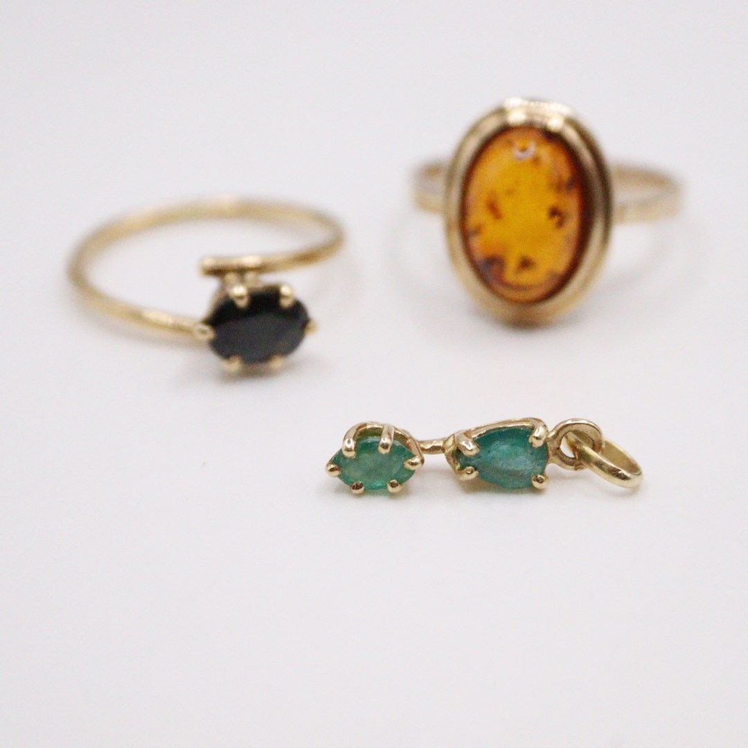 Null 一套两个18K(750)黄金戒指，镶有一颗椭圆形蓝宝石和一颗凸圆形琥珀。附有一个18K（750）黄金吊坠，上面有两颗绿宝石。 
毛重：8.1克。