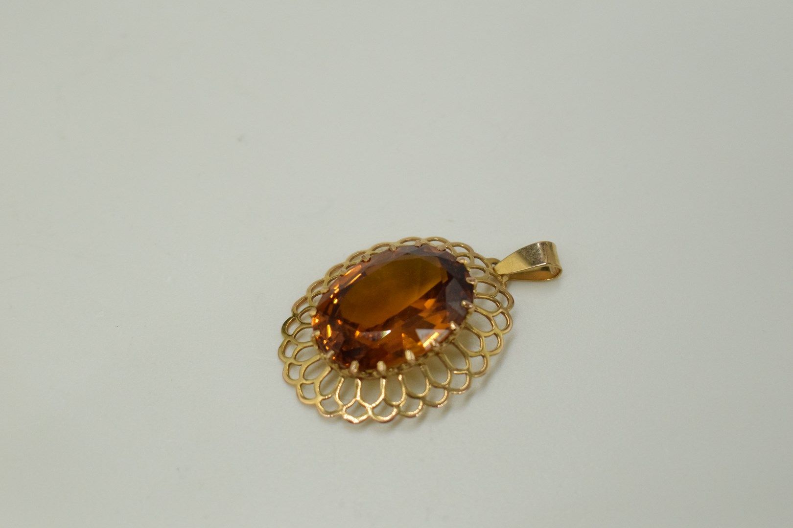 Null 18K（750）黄金椭圆形镂空吊坠，镶嵌一颗合成橙色蓝宝石。 
毛重：6.9克。