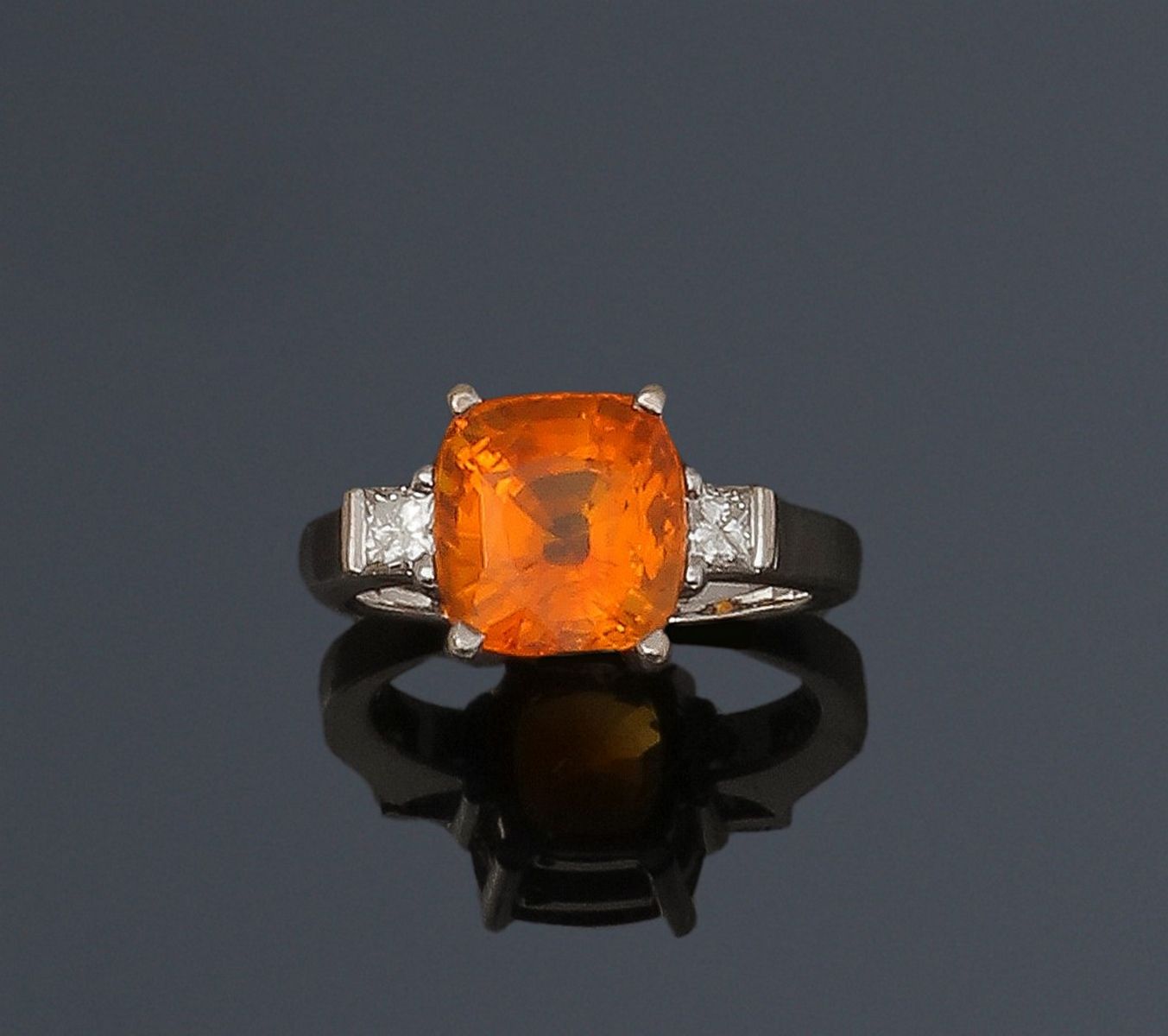Null 18K(750)白金戒指，镶嵌着一颗枕形的橙色蓝宝石，上面有两颗公主钻。手指尺寸：52/53。蓝宝石尺寸：约9.7 x 9.2 x 6.7毫米。毛重：&hellip;