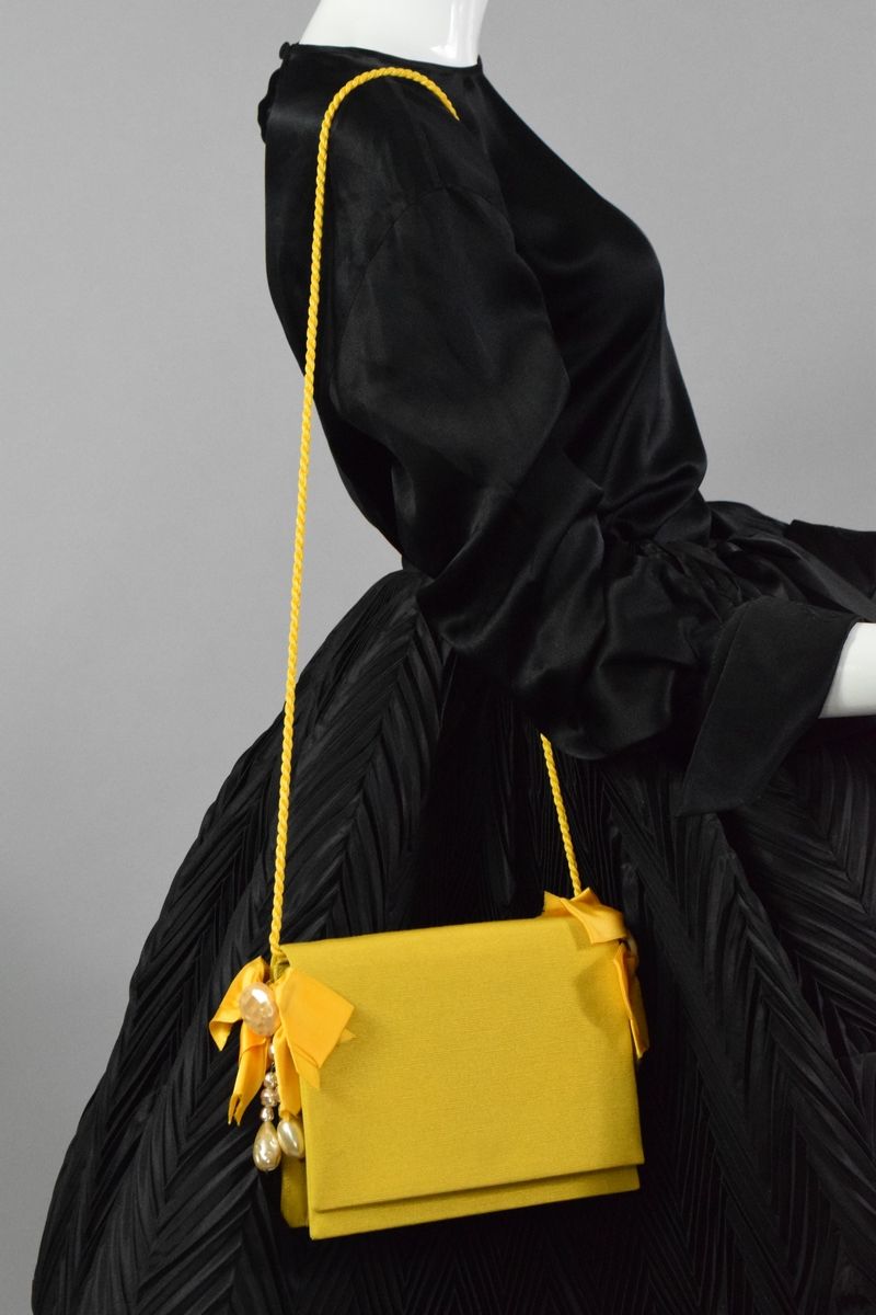 Null 克里斯蒂安-迪奥专卖店
约1980年

罕见的手拿式手袋或肩包，覆盖着黄色的奥特曼，两端有大的装饰物，装饰着花式珍珠和黄色丝带，点缀着一条可拆卸的同色&hellip;
