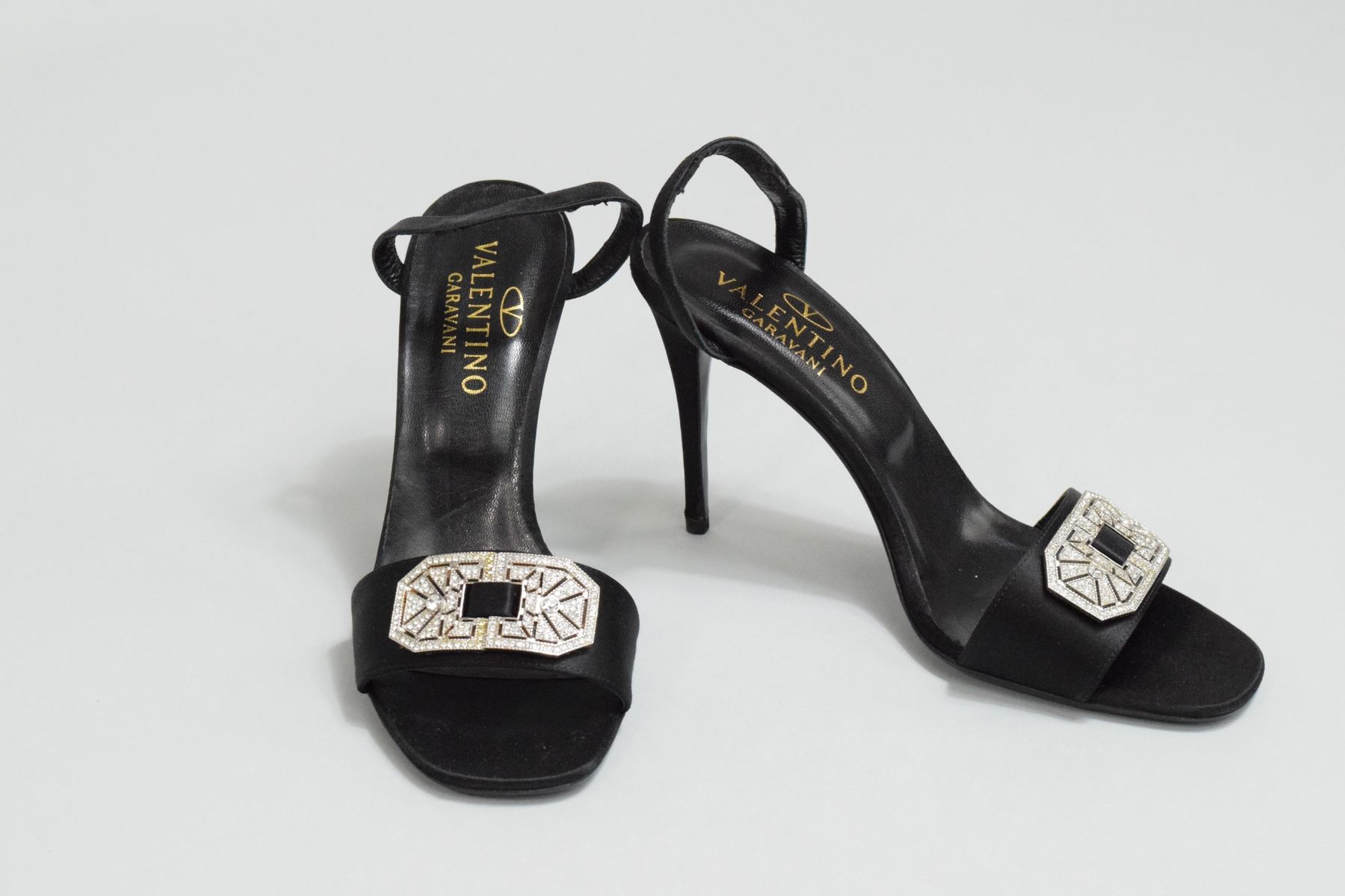 Null 梵蒂诺 

一双黑色缎子高跟凉鞋，鞋面上有丰富的艺术装饰胸针。
非常轻微的磨损。 

尺寸：38 1/2
鞋跟高度：10厘米