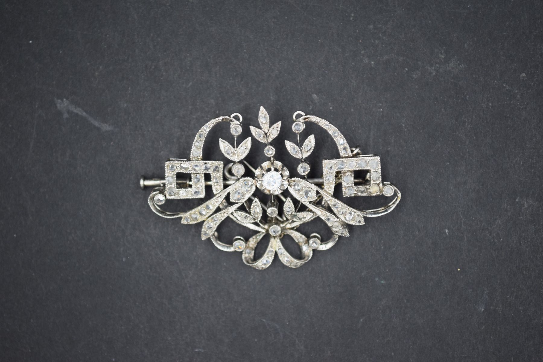Null Broche en or gris 18k (750) à décor de volutes ornées de diamants. 
Circa 1&hellip;