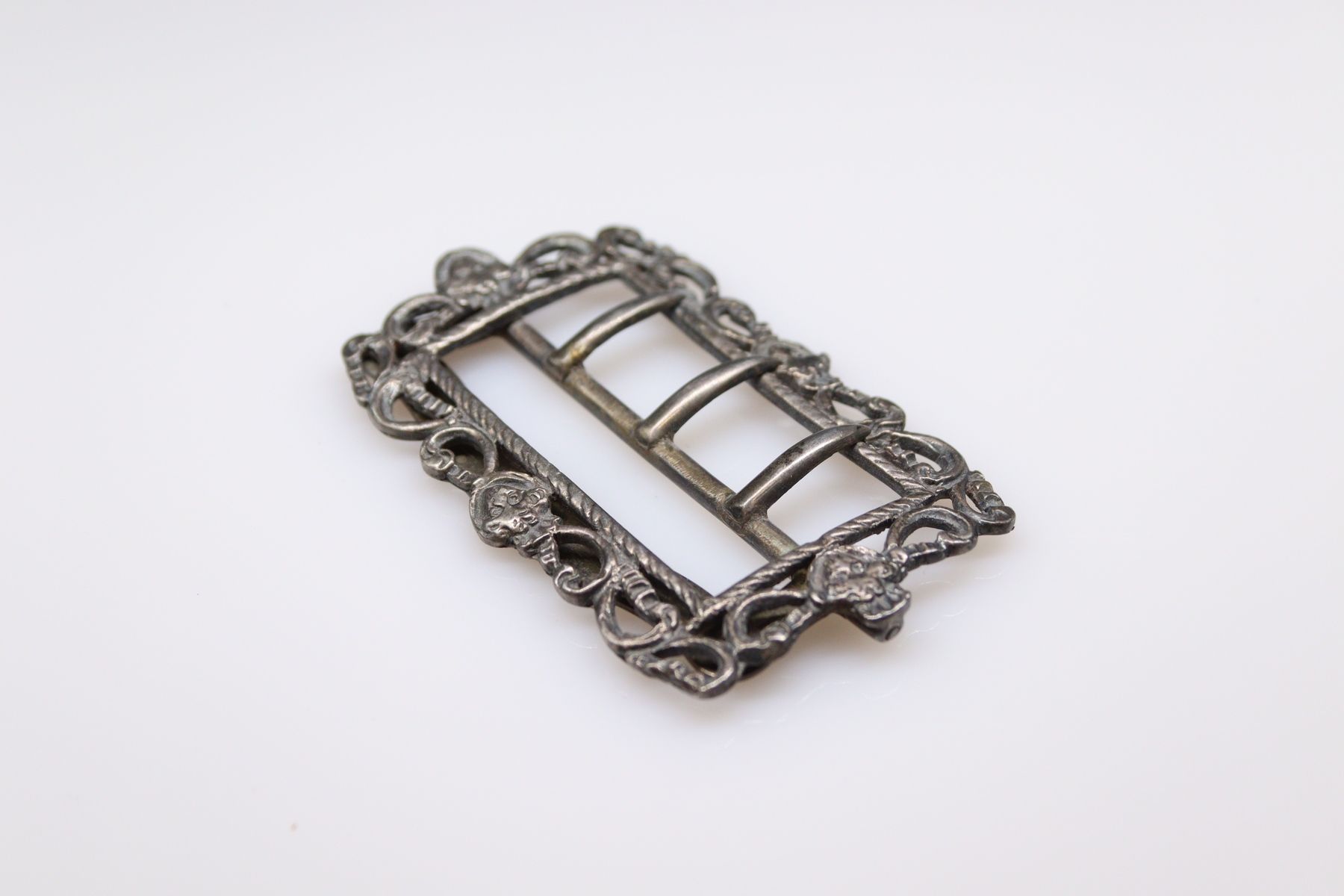 Null Rectangular silver buckle (800) with corded decoration and masks.
English w&hellip;