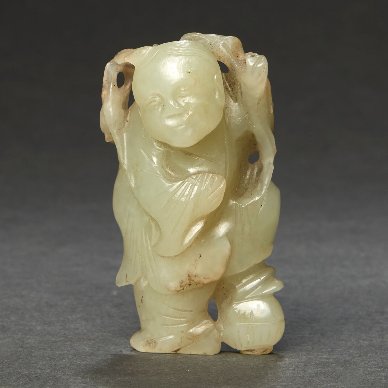 一件青瓷玉器 ，表现了一个手持莲枝的孩子，脚踩在一个盒子上。 （石头的碎片和自然缺陷）。 中国，19世纪。 玉雕儿童像，中国，19世纪。 高6厘米(2 3/8英&hellip;