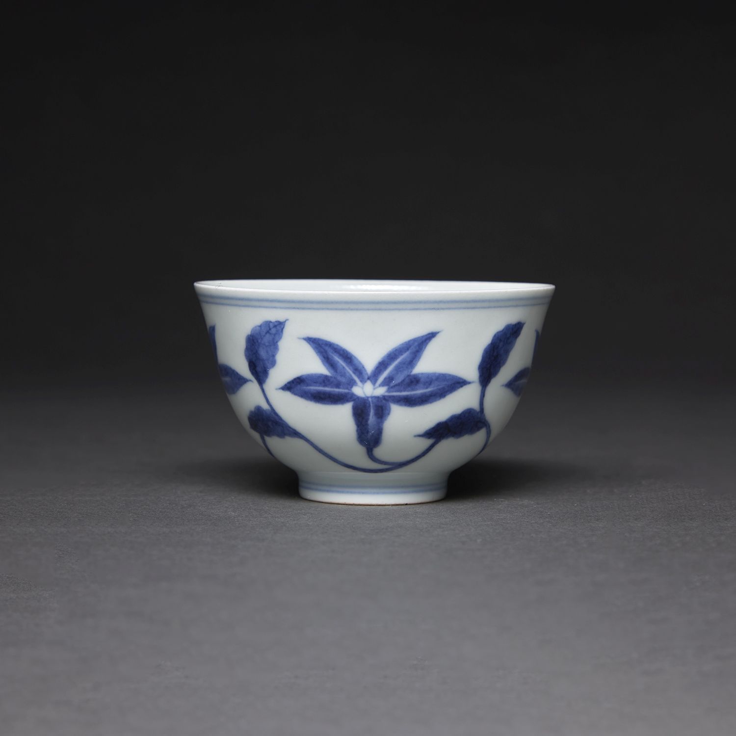 Null 小杯
白蓝色瓷器，饰以花茎。底部有成化皇帝的伪作标记。
中国，20世纪。
-
青花瓷小杯，中国，20世纪。
直径。8 cm (3 1/8 in.)