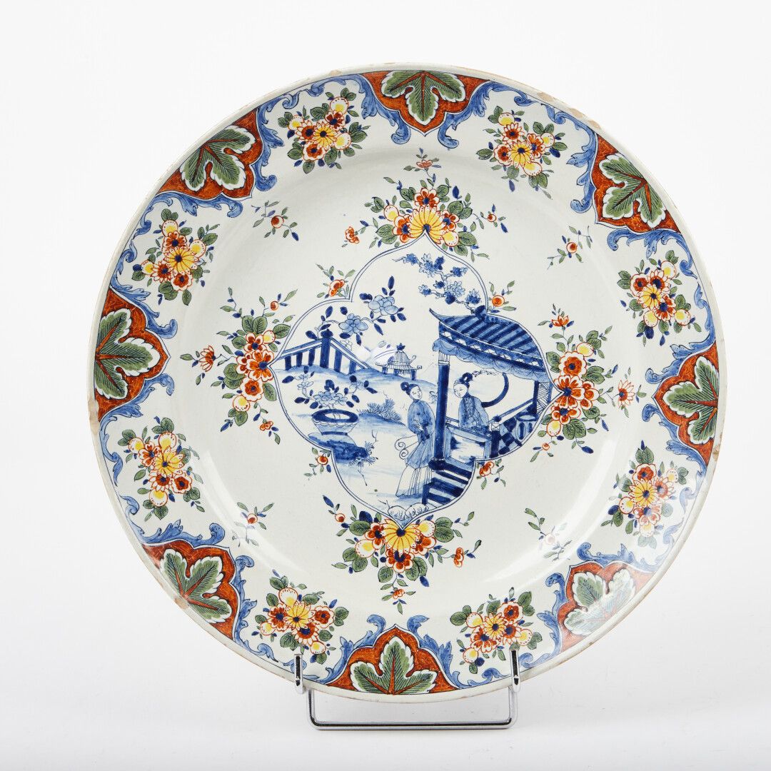 Null 代尔夫特风格。

陶器盘子，中央有中国妇女的蓝色单色装饰，边缘有多色花。

直径：37厘米。