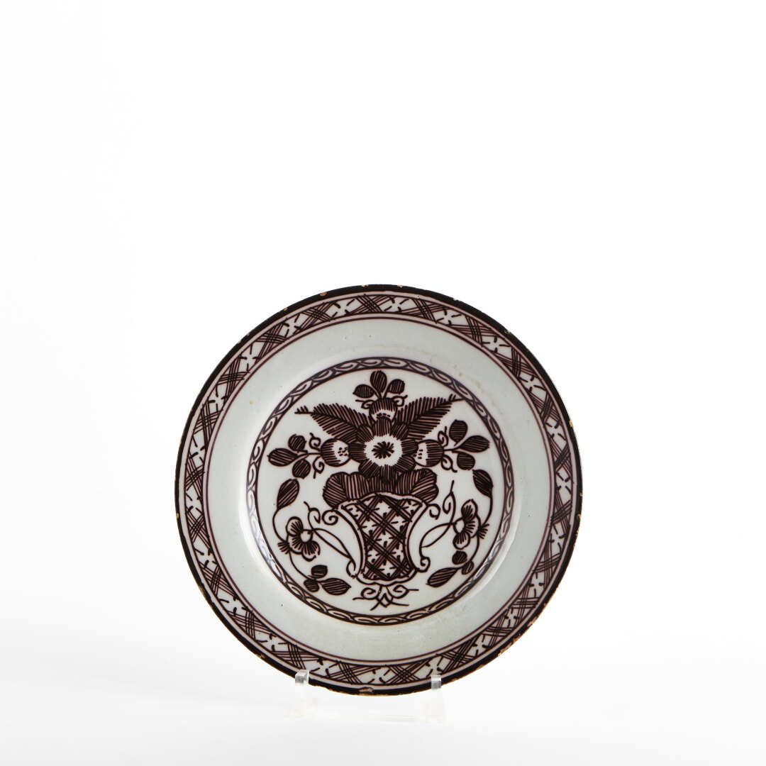Null 德尔福

锰质浮雕装饰的陶盘，上面有一个风格化的花瓶。

18世纪晚期。

直径：22.5厘米。