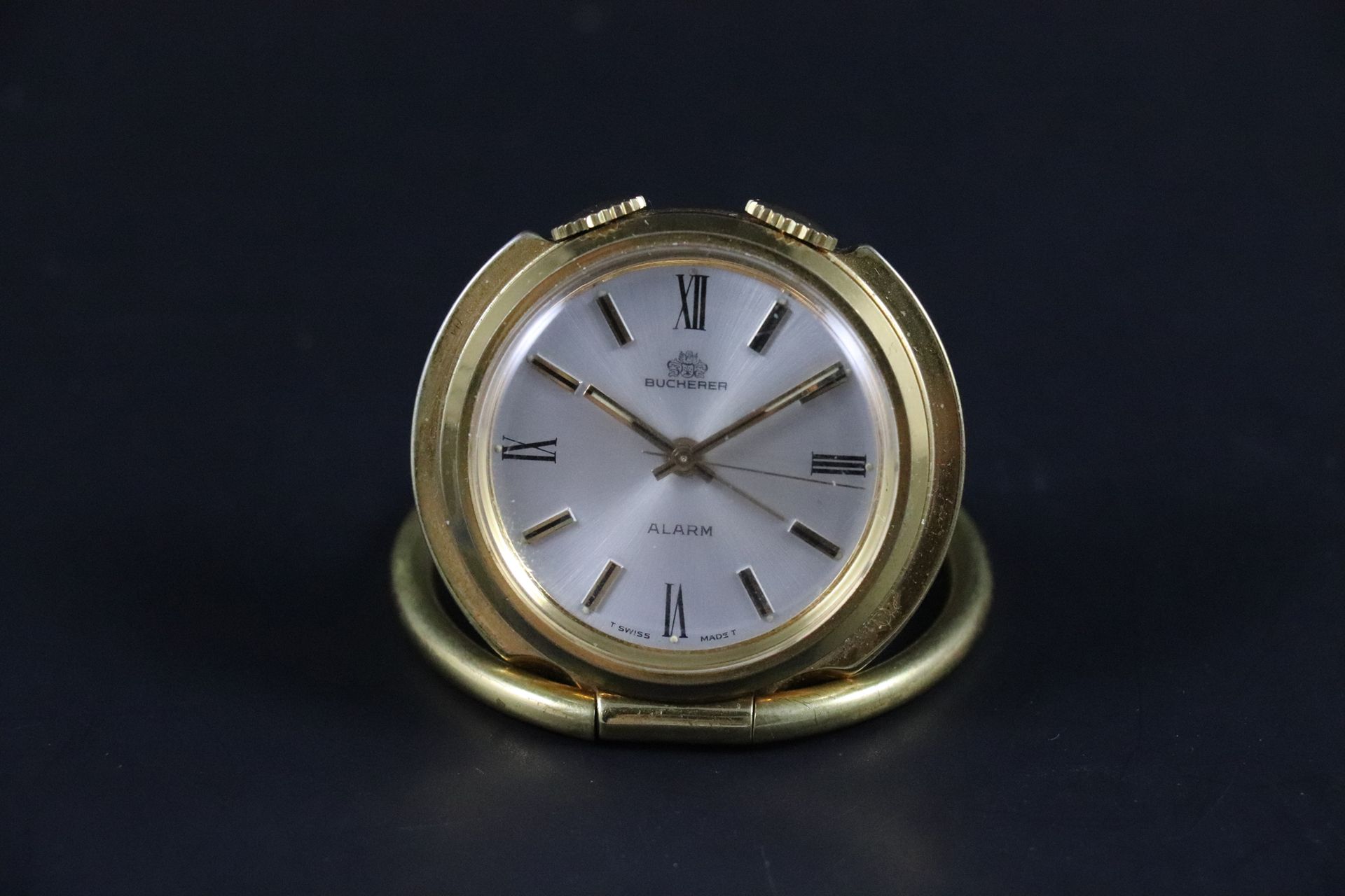 Null 
布赫勒

旅行钟 - 闹钟，约1960年

鎏金金属旅行或口袋闹钟，有光滑的边框（充当底座）。银色拉丝表盘上有巴顿式刻度，第三根指针用于设置闹钟。1&hellip;