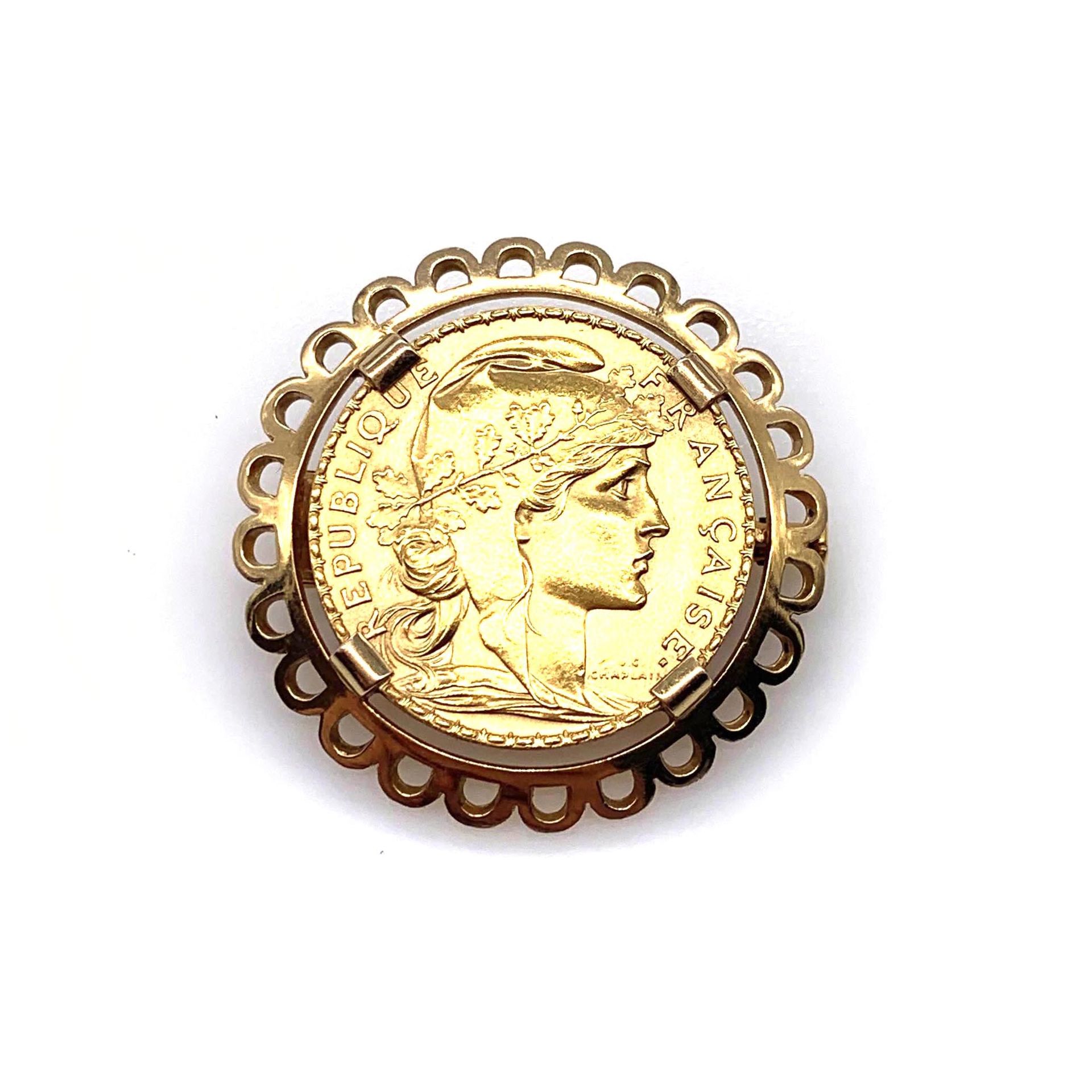 Null 介绍1909年法国共和国20法郎硬币的宣传册。18K黄金花瓣框架。法国的工作。 直径：3厘米。 毛重：11.87克。 一枚黄金硬币胸针。