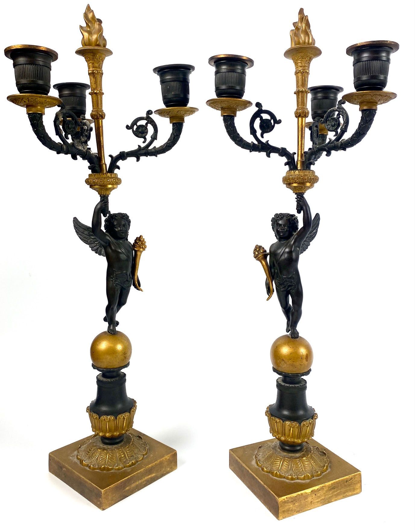 Null 一对镀金和斑驳的青铜烛台，装饰有小天使，手持三个灯臂和一个燃烧的火炬。查理十世时期。高度：47厘米
