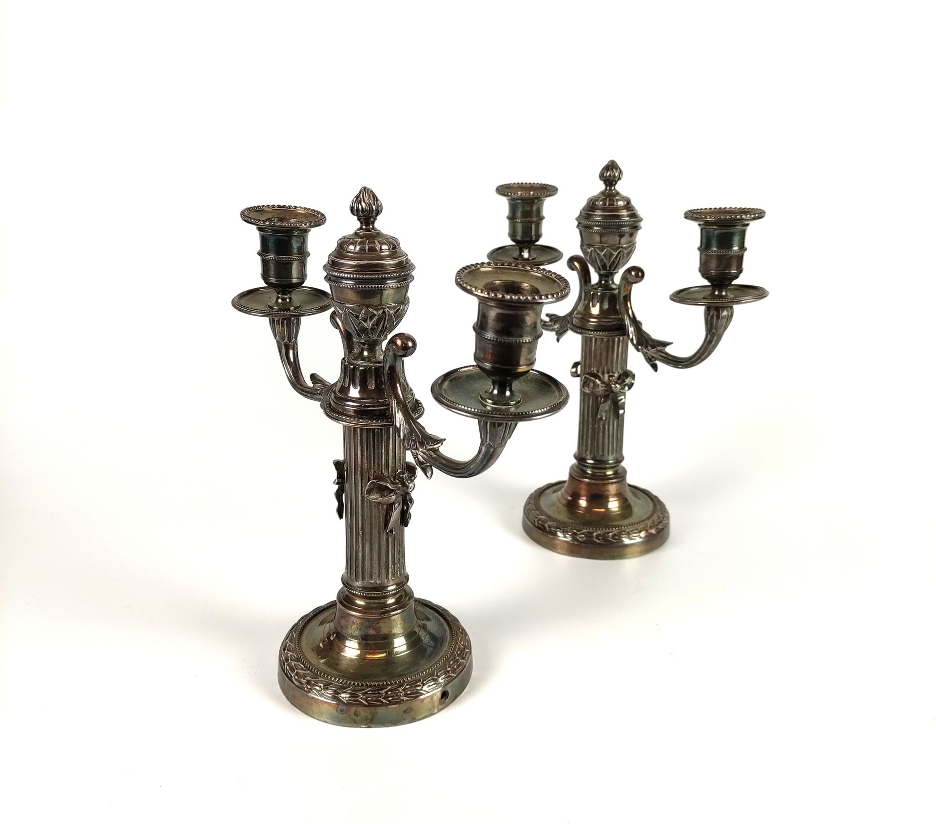 Null 一对银制铜制烛台，两只灯臂放在有凹槽的柱子上，上面装饰着丝带。中心臂上装饰着一个火盆。路易十六风格 高度：26厘米（穿孔