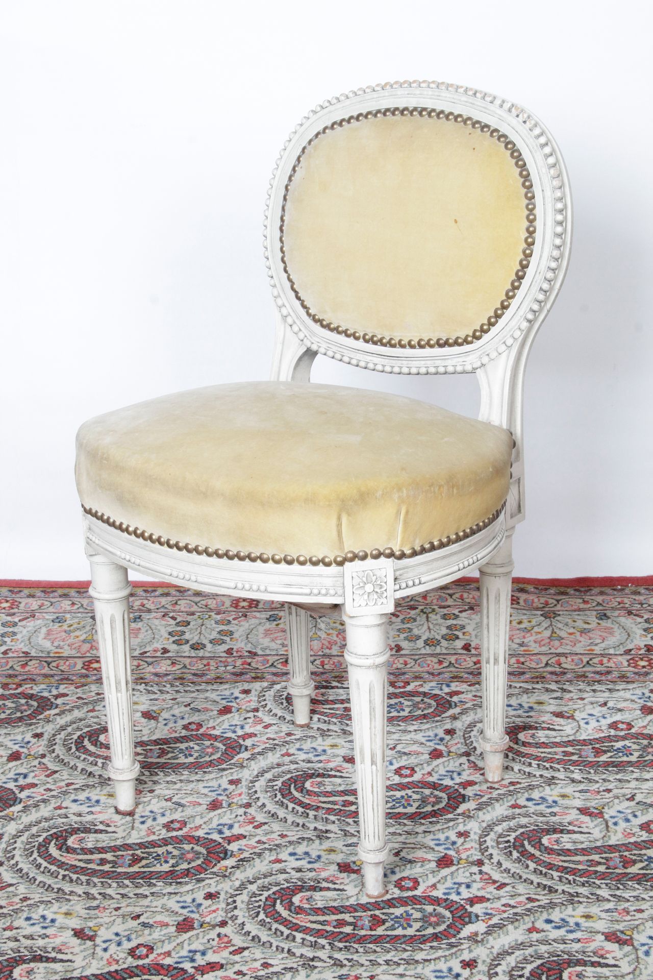 Null 一把路易十六风格的小型理发椅，奶油色的木头上有一个奖章式的靠背，雕刻着珍珠和玫瑰花纹的造型。它站在锥形的、有凹槽的和有鱼鳍的腿上。米色天鹅绒内饰（污渍&hellip;