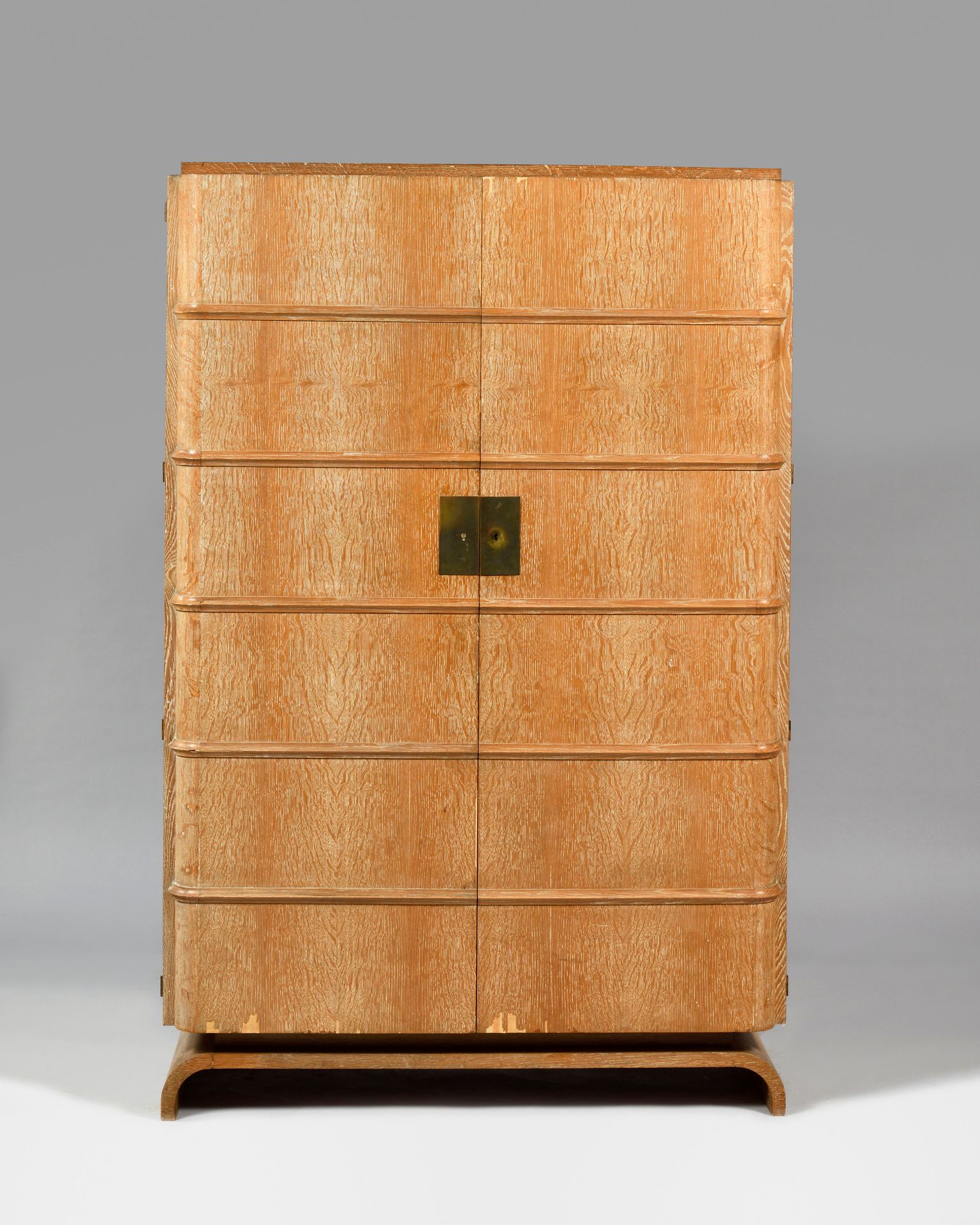 Null 1930年代的作品 橡木贴面的柜子，有两扇门，装饰着五个弯曲的芦苇，在一个略微凹陷的拱形底座上，露出一个衣柜和不同高度的架子（没有架子） 缺少钥匙 缺&hellip;