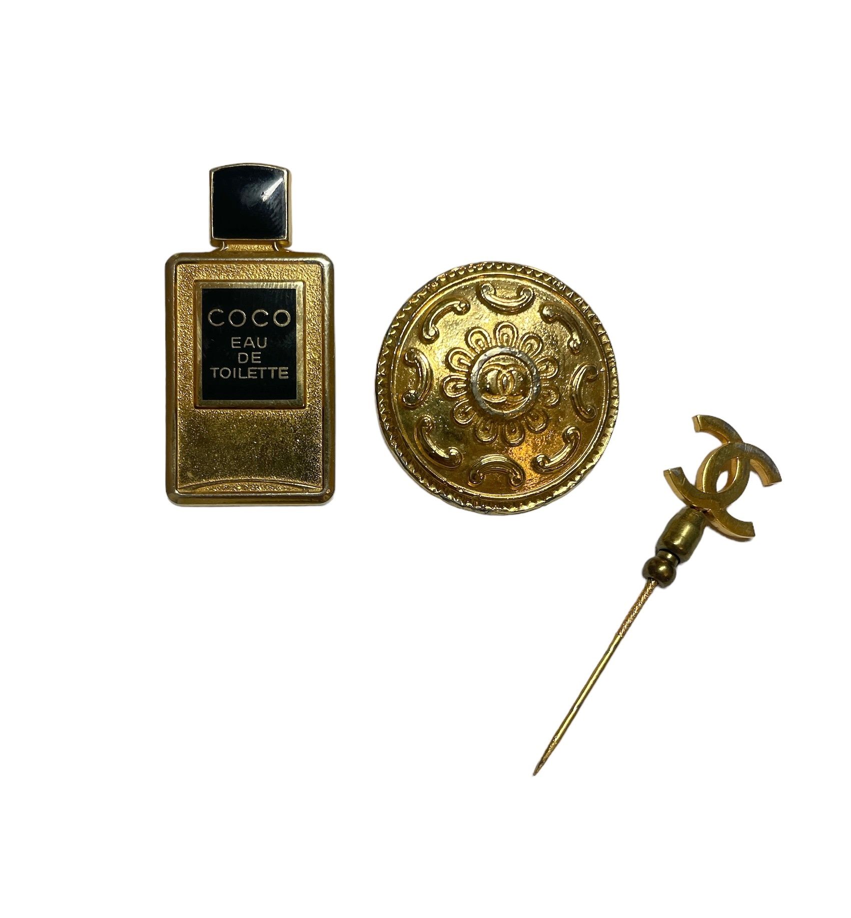 Null 香奈儿
带有 "COCO "淡香水标志的胸针，伴有一个领带针，上面有品牌标志和一个在背面签名的金色按钮