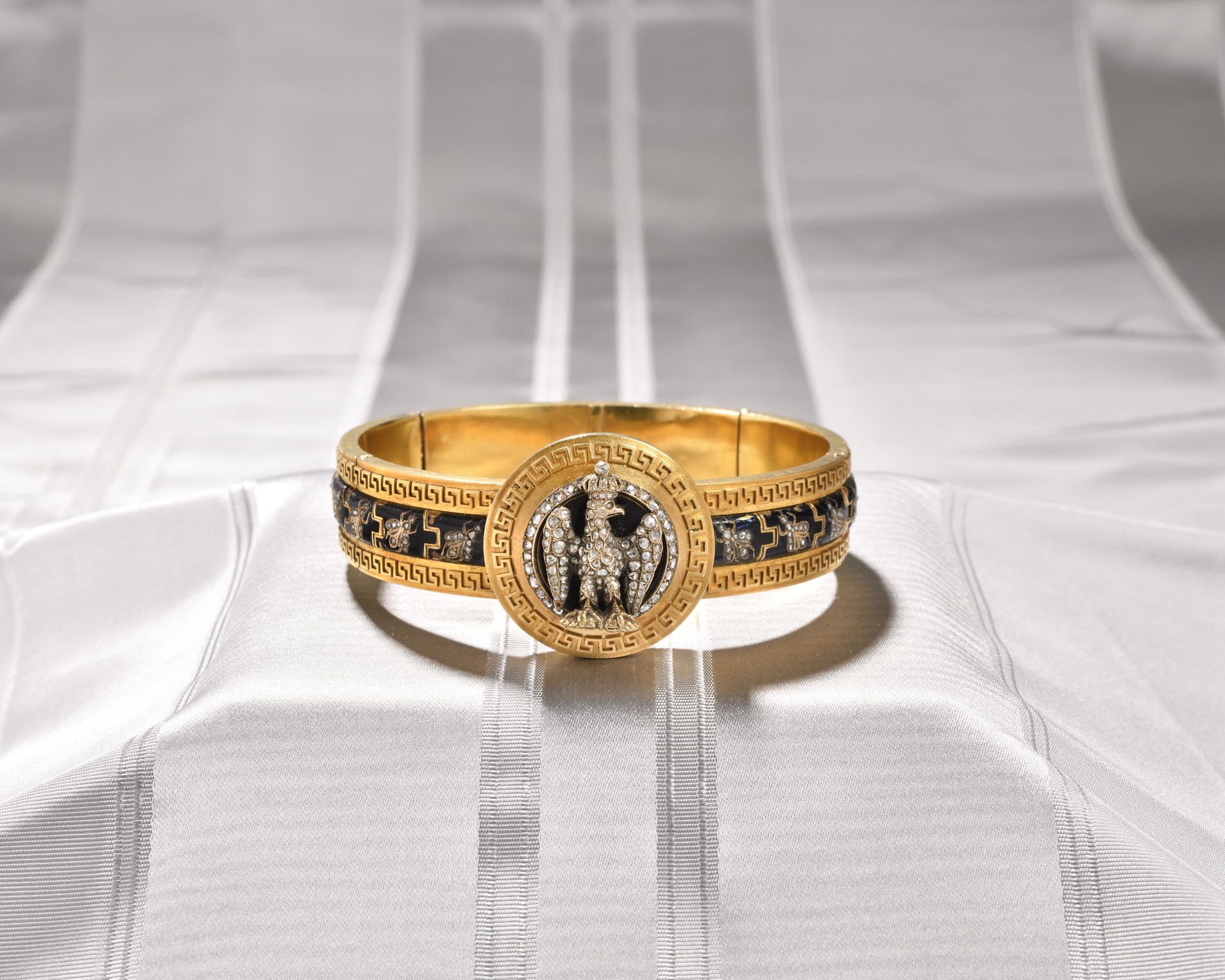 Null 手镯，半刚性的主体由六个黄金链节组成 
中间有一个圆形的凹面奖章，边缘装饰有希腊式的门楣，上面有一个浮雕式的蓝色珐琅奖章，上面有一只加冕的帝王之鹰，环&hellip;
